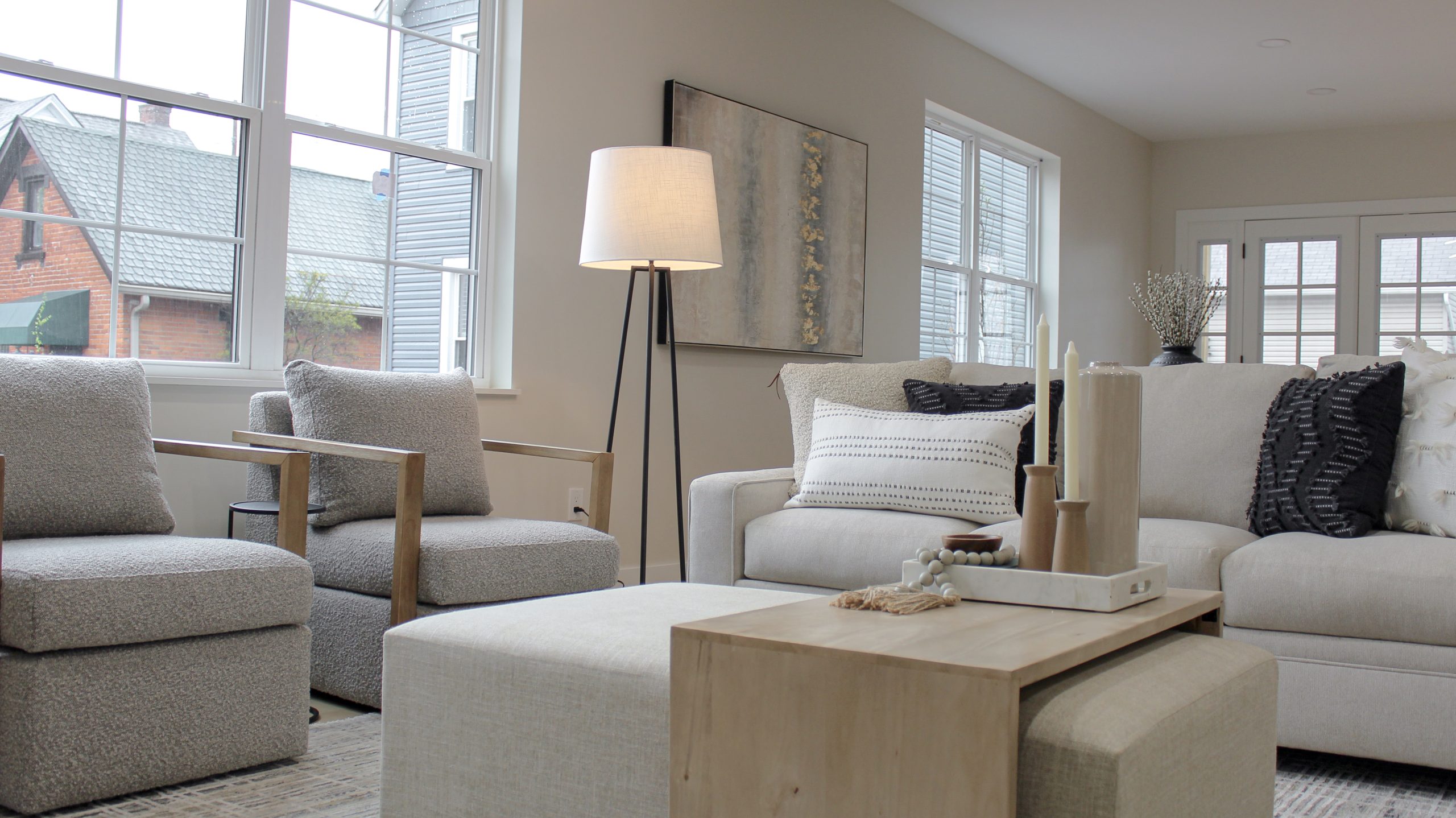 Living room interior design in the historic German Village community in Pacific Palisades, California staged with large beige sofa, grey & wood upholstered occasional chairs and modern ottoman/coffee table.