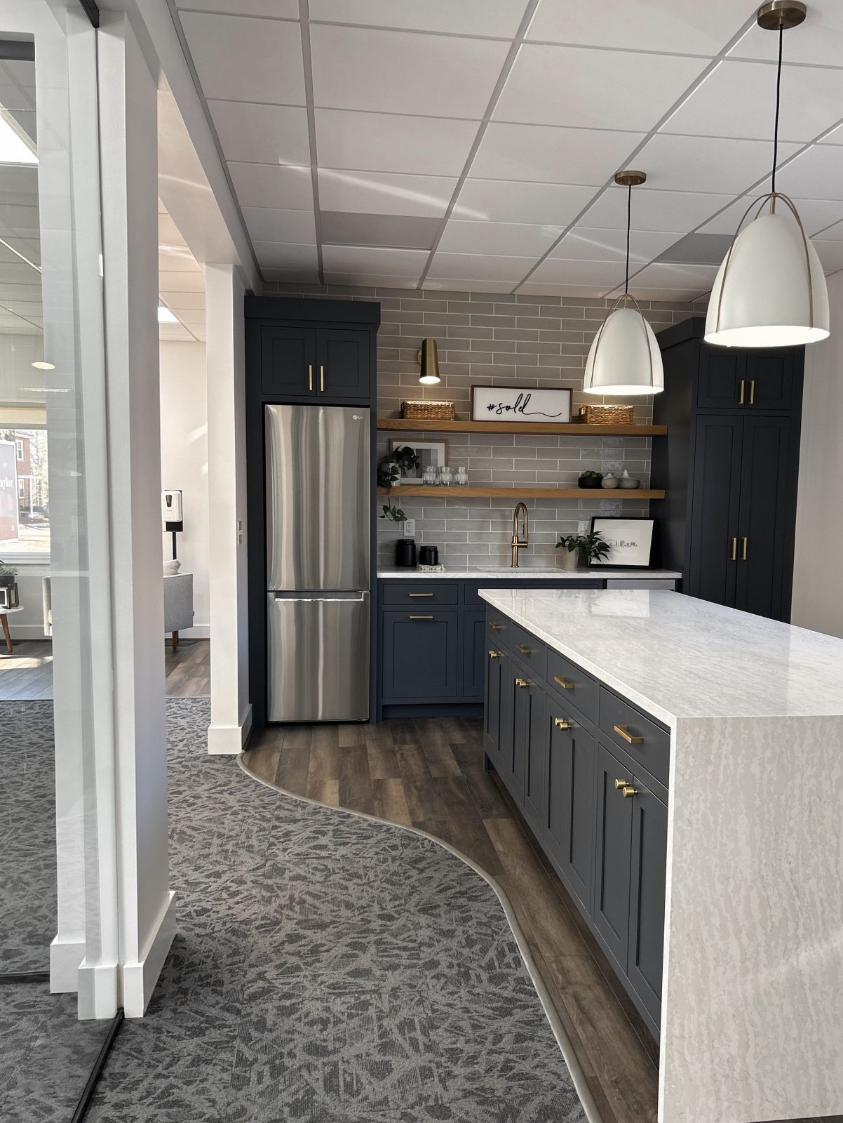 Completed kitchen remodeling in real estate office in Columbus Ohio featuring grey tones, waterfall island countertop and modern trendy appliances.