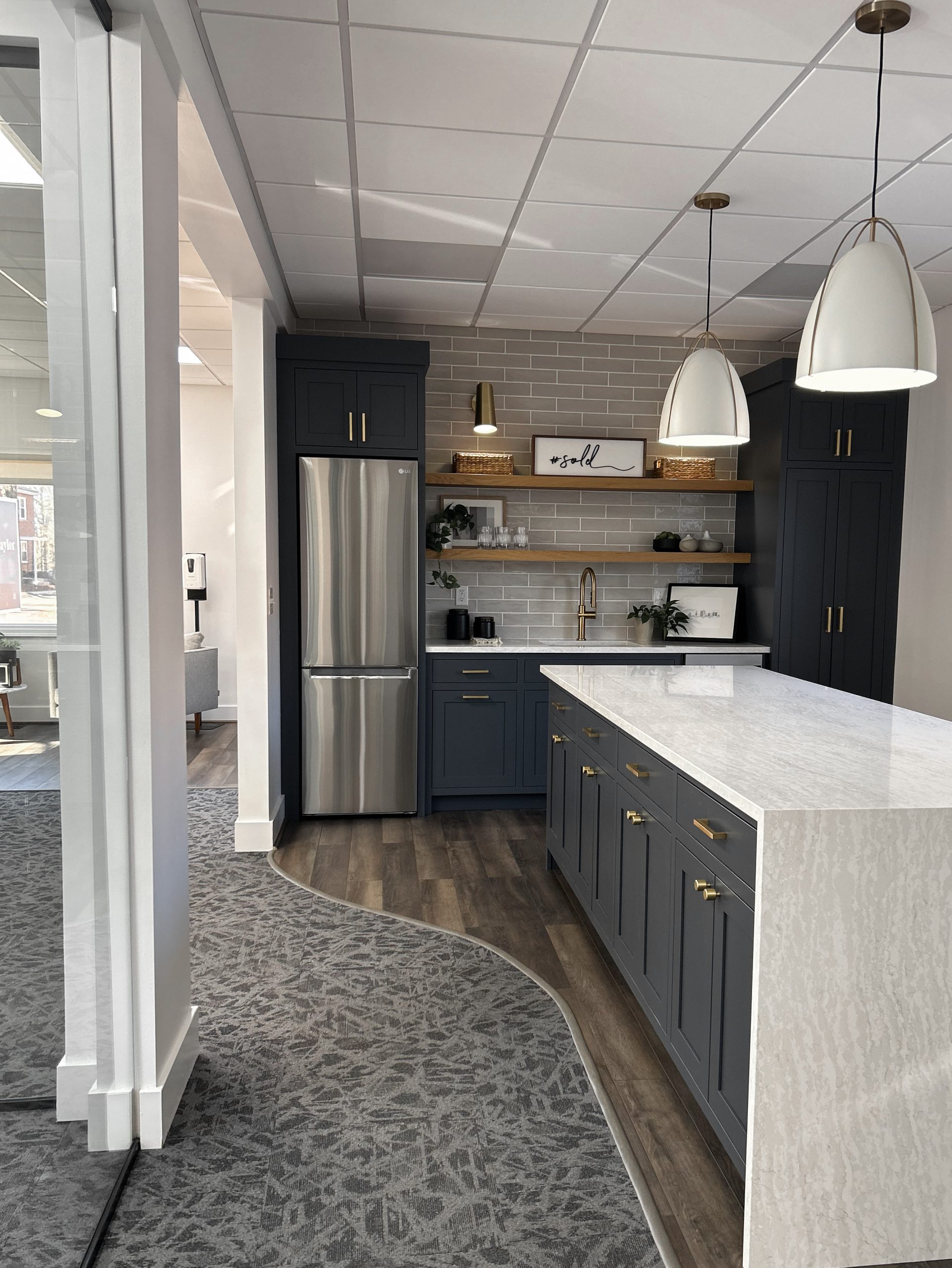 Completed kitchen remodeling in real estate office in Columbus Ohio featuring grey tones, waterfall island countertop and modern trendy appliances.