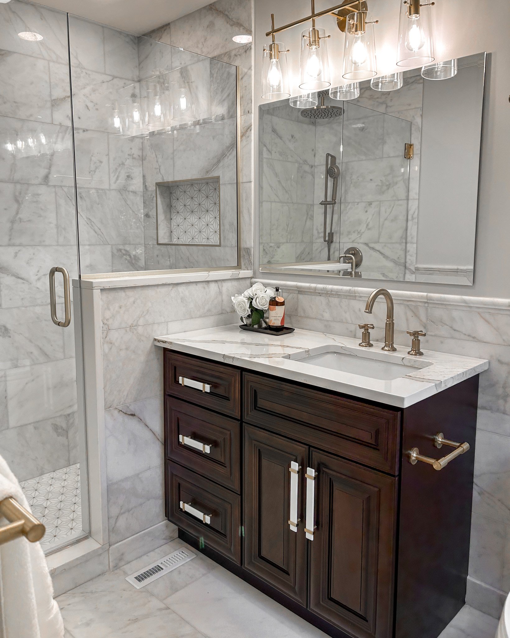 Redesigned luxury bathroom in Upper Arlington, Ohio, with marble tile, walk-in shower, and custom dark wood vanity.