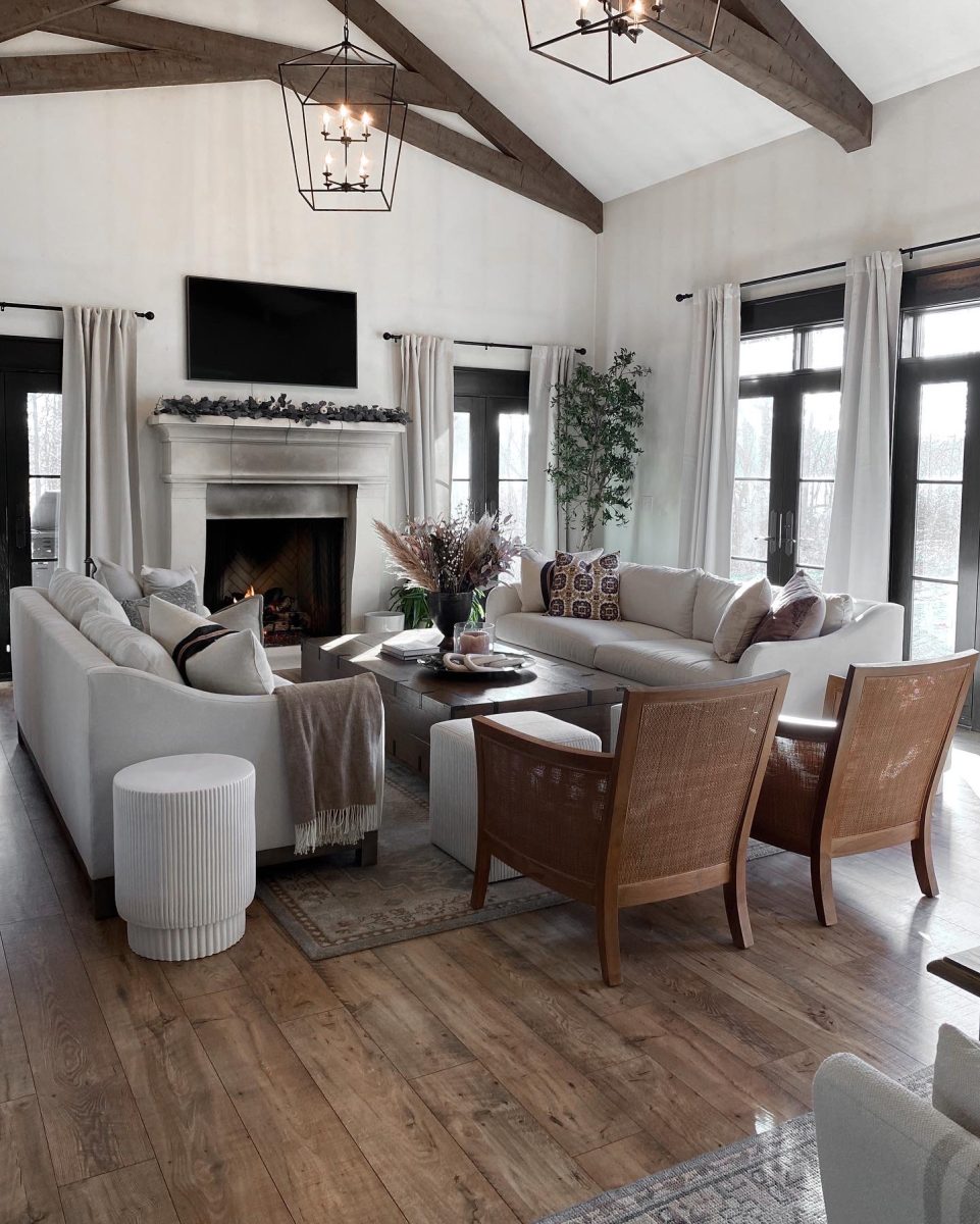 Large luxury living room with two modern sofas, leather occasional chairs, large coffee table chest and wood burning fireplace