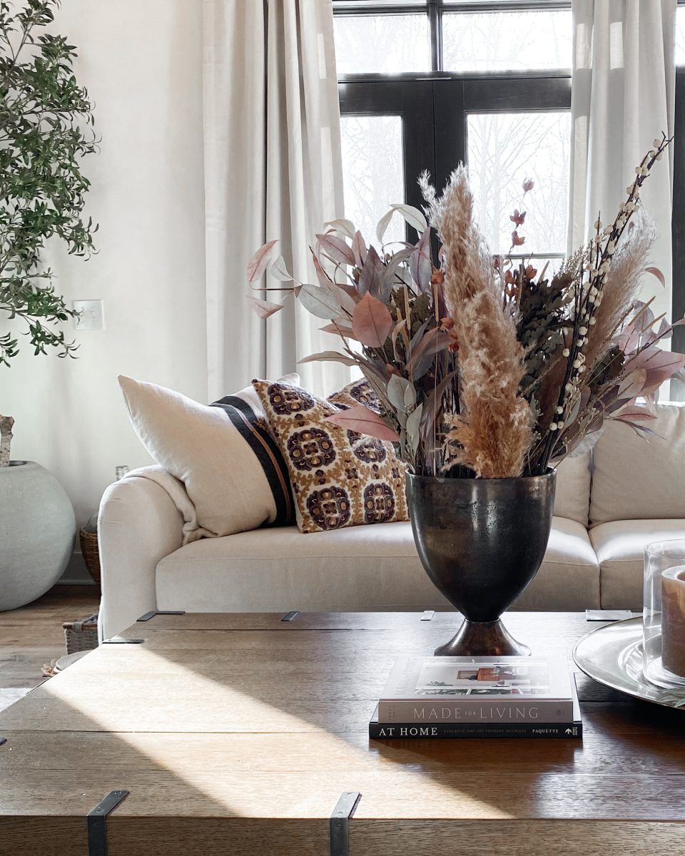 Large coffee table decor with ornate vase, faux decorative plants and candles.