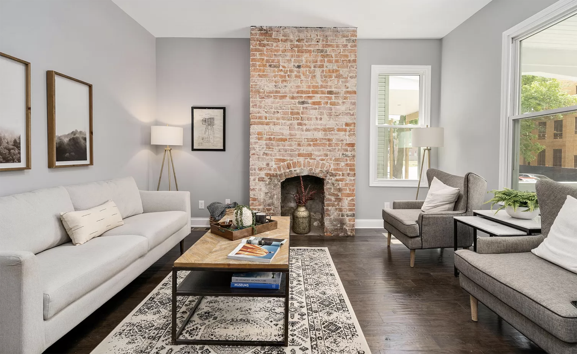 Living room design with exposed brick, modern occasional chairs, sofa and coffee table.
