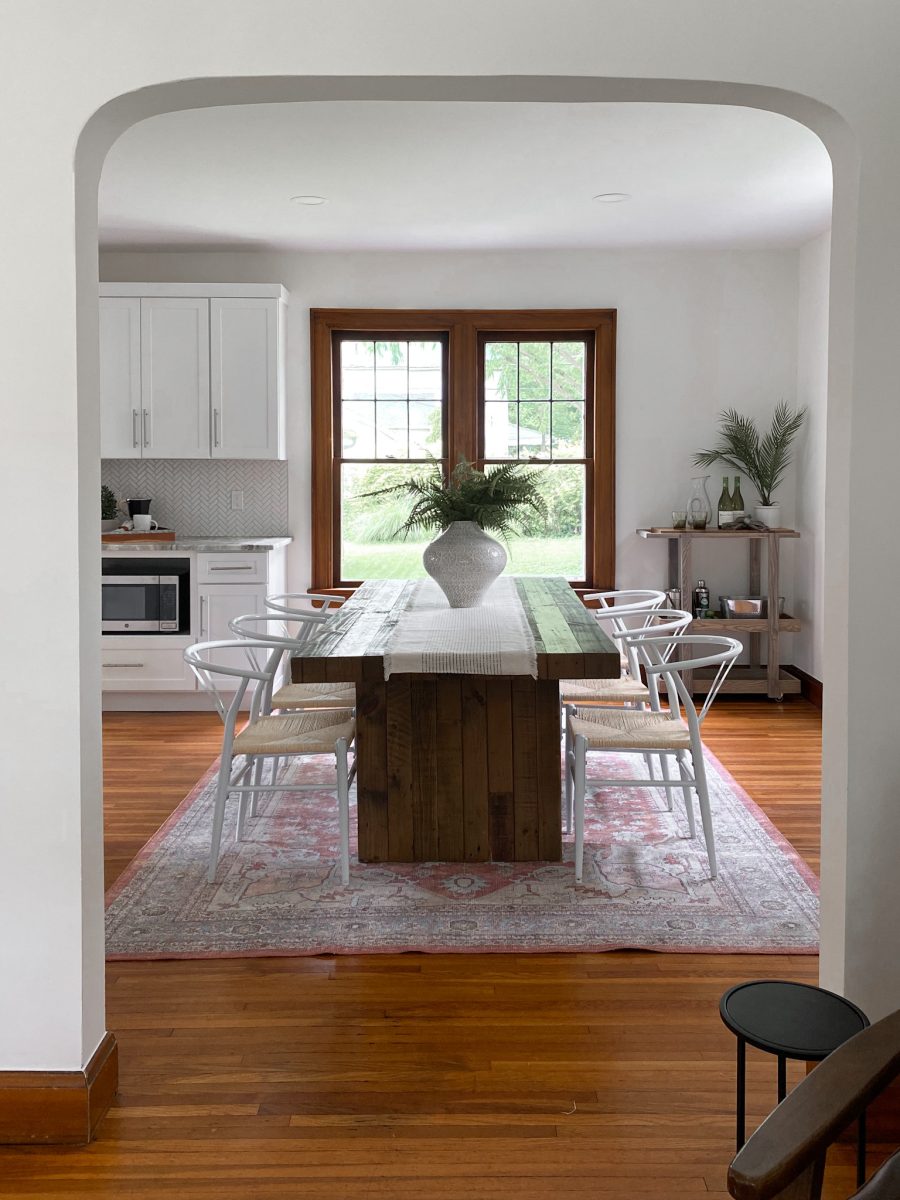 Staged dining room in Clintonville, Ohio home showcases faux greenery, bar-cart, ornate area rug and large dining table.