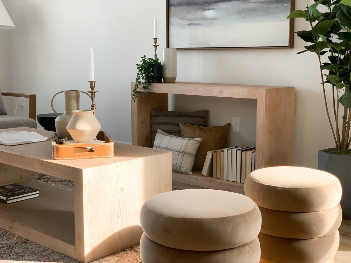 Modern wood console and coffee table with suede ottomans and clay vases.