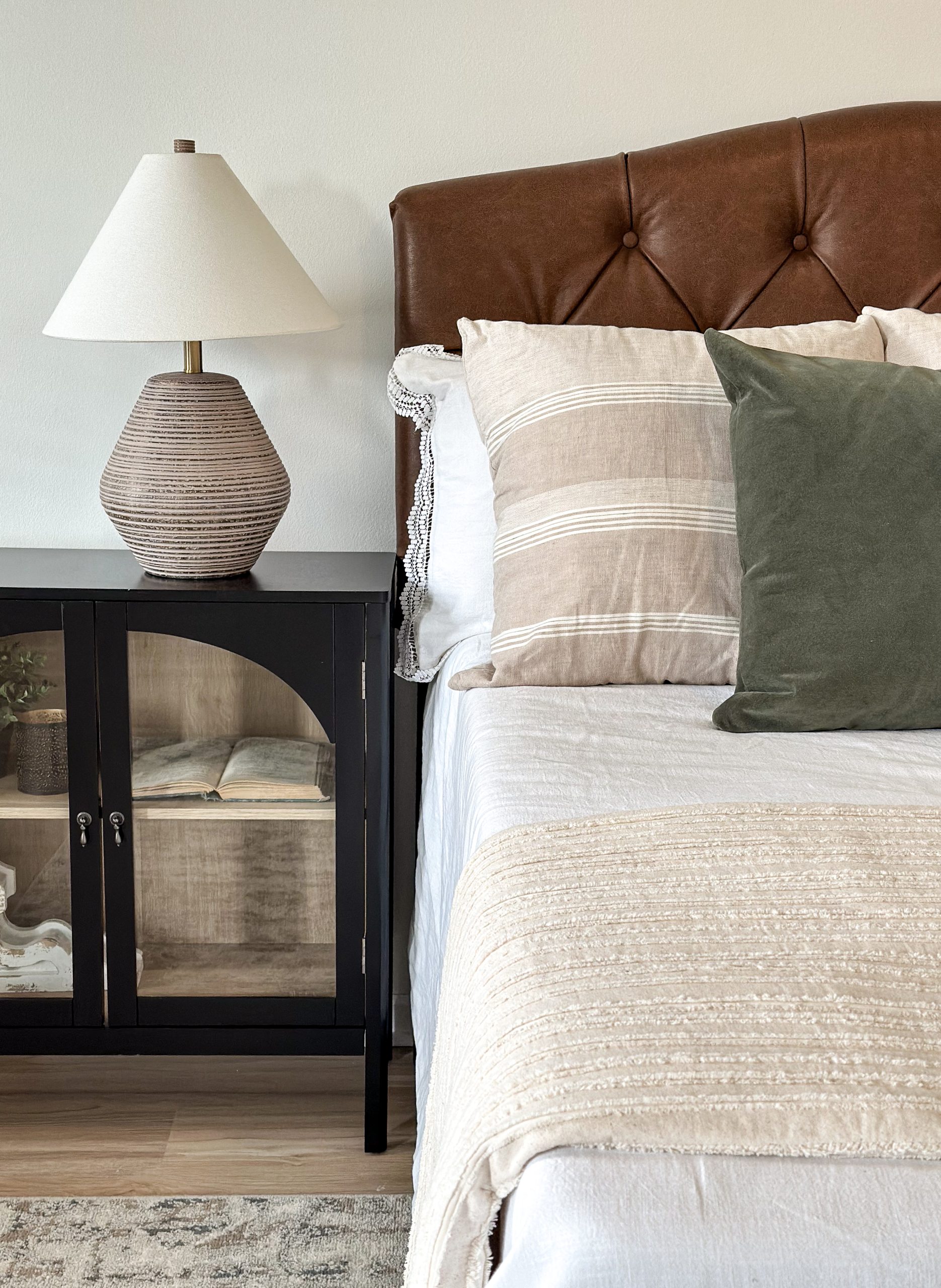 Dublin, Ohio, primary bedroom staging with leather tufted headboard, glass inlay nightstands and table lamps.