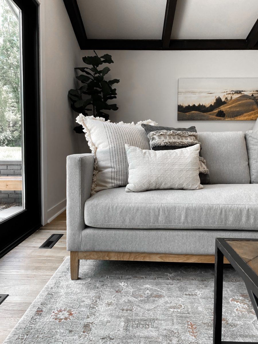 A detailed look at a chenille sofa, assorted throw pillows and ornate living room area rug