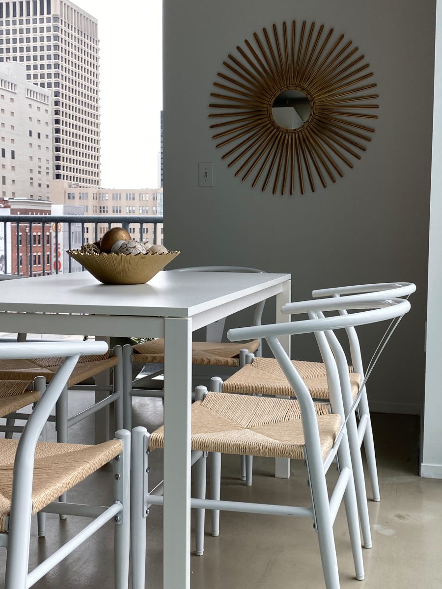 A small kitchen dining area in a high rise condo in downtown Columbus features white minimal table, and modern whicker chairs.