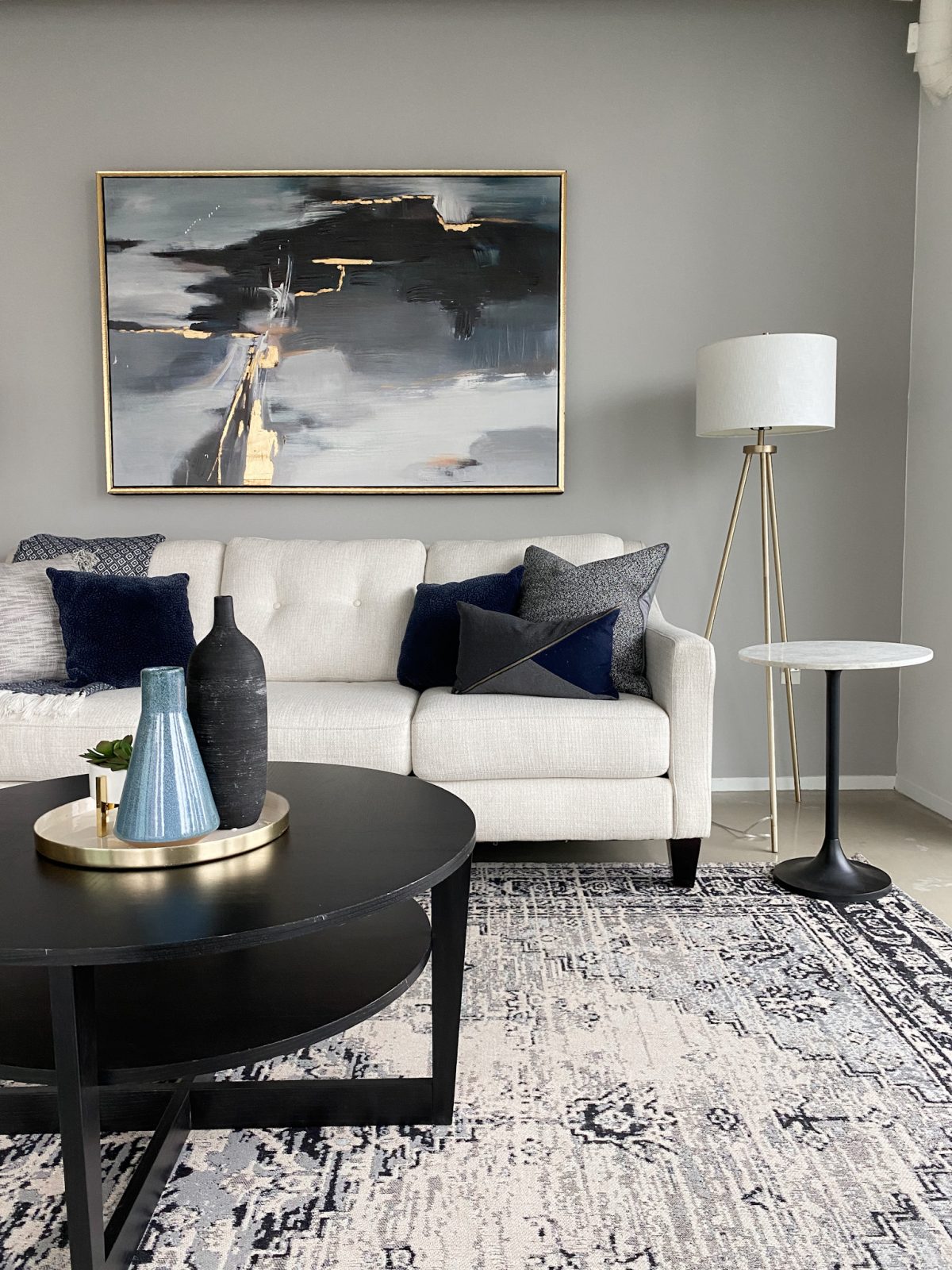 Luxury living room staging showcasing a white sofa, black coffee table, floor lamps and abstract art.