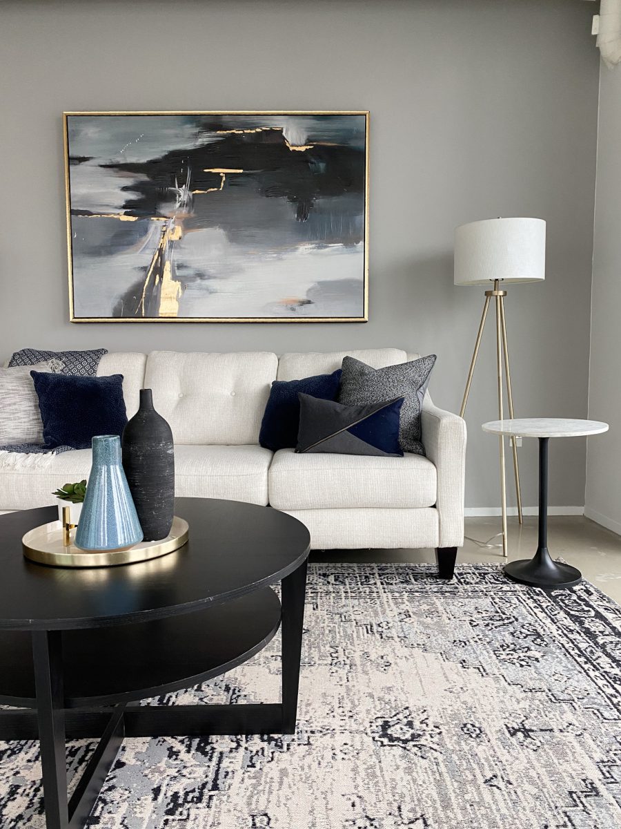 Luxury living room staging showcasing a white sofa, black coffee table, floor lamps and abstract art.