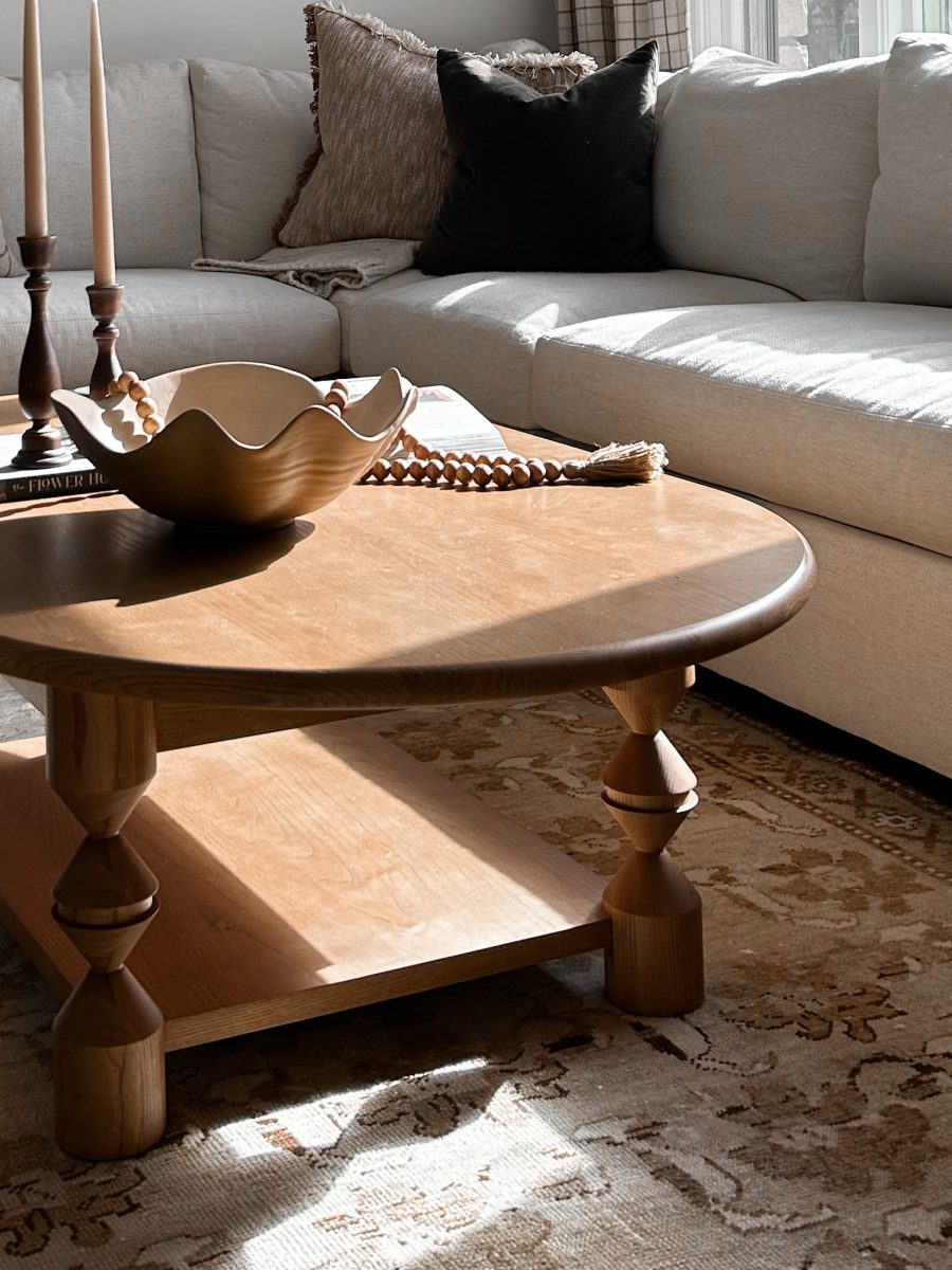 Modern luxury wooden coffee table placed on woven rug in front of large sectional sofa to complete an interior design project in Pacific Palisades, California.