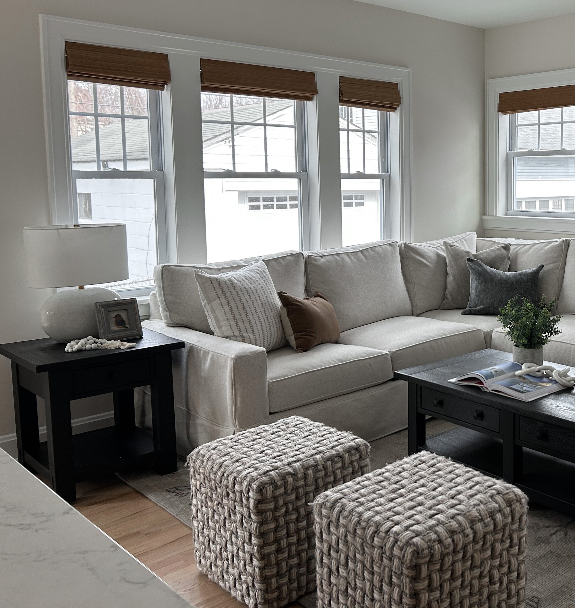 Light, comfortable living room design for residential interior design client featuring unique black stained coffee table and large sectional soffa.