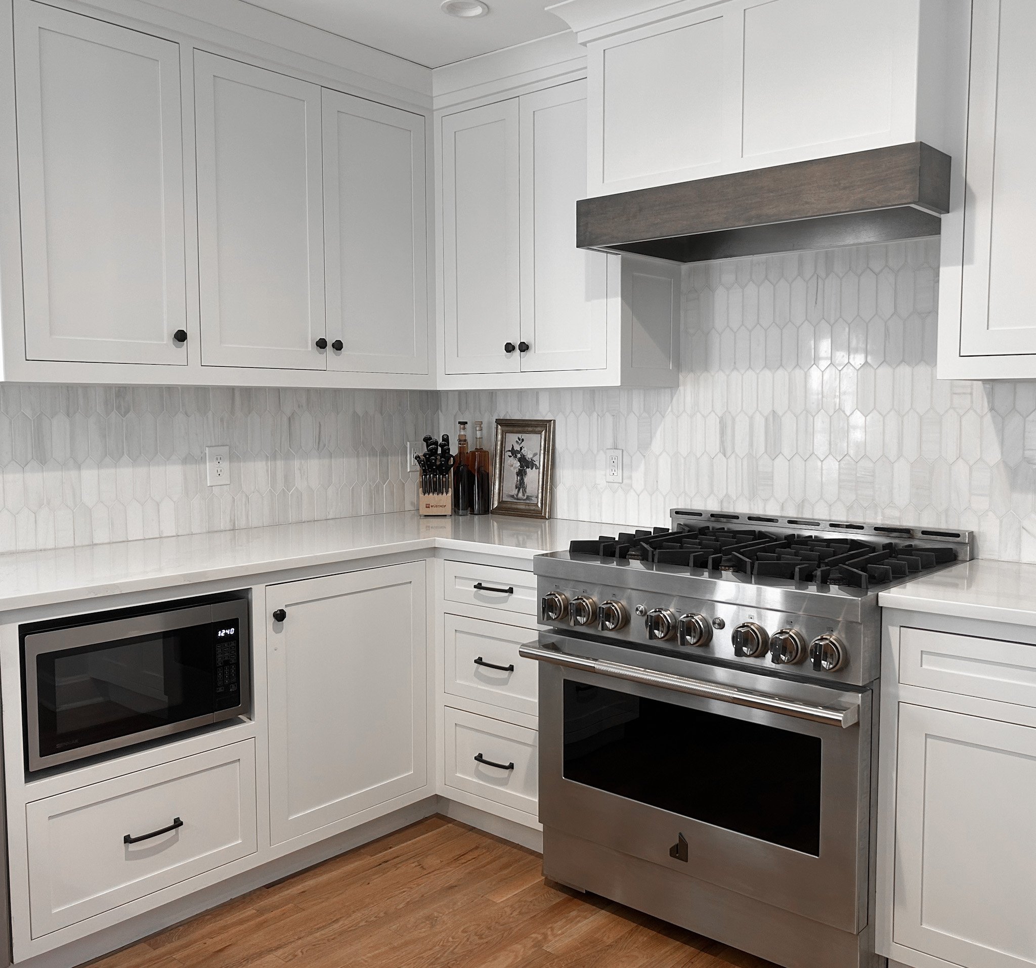 White themed kitchen area with white countertops. custom cabinets and white backsplash.
