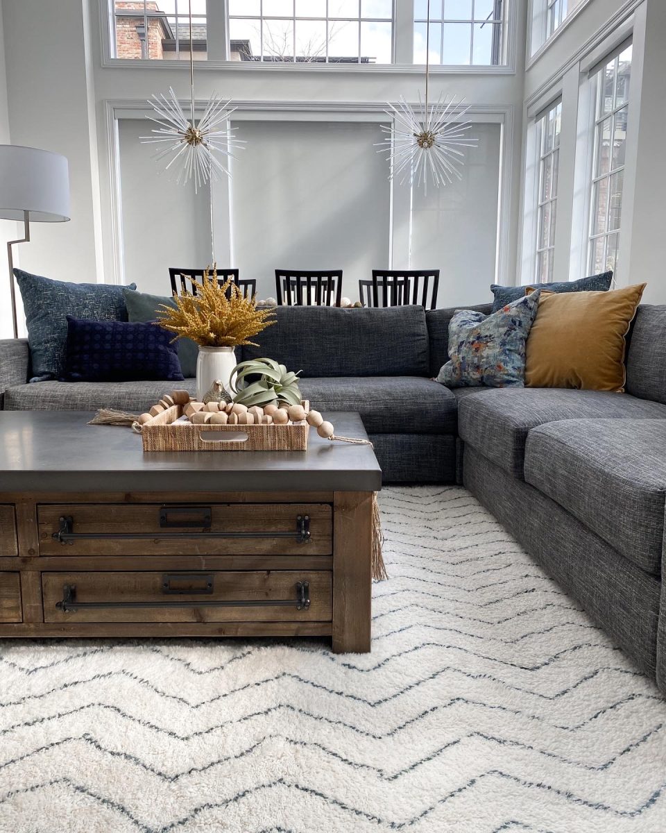 A large spacious living room with sectional sofa, industrial wood and stone coffee table and floor to ceiling windows in Pacific Palisades, California's arts district.