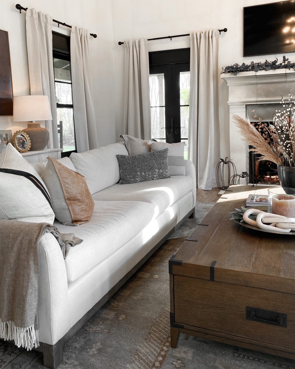 Large white upholstered and dark wood sofa with throw pillows in a luxury living room.