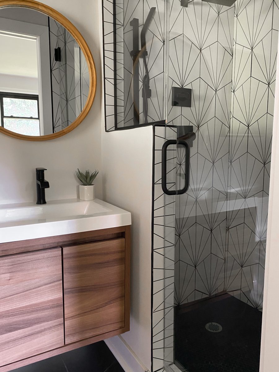 A modern remodeled bathroom in a Pacific Palisades, California home staged with faux greenery and round hanging mirror.