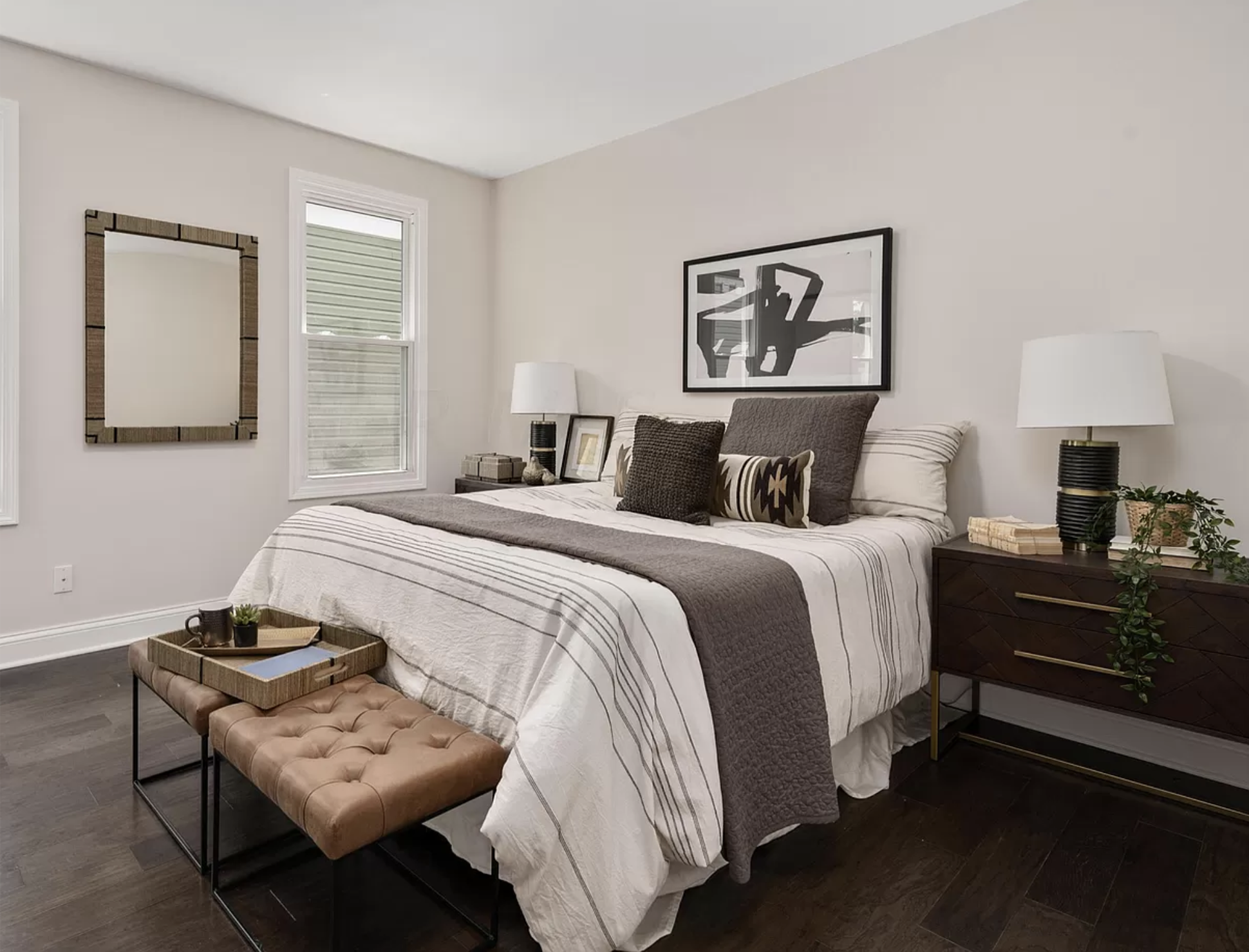 A primary bedroom design with natural colors, wooden night stands and modern table lamps.