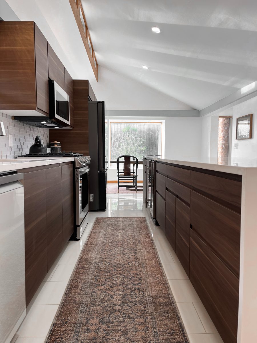 remodeled kitchen in Pacific Palisades, California with long rug, dark stained cabinetry and modern appliances.