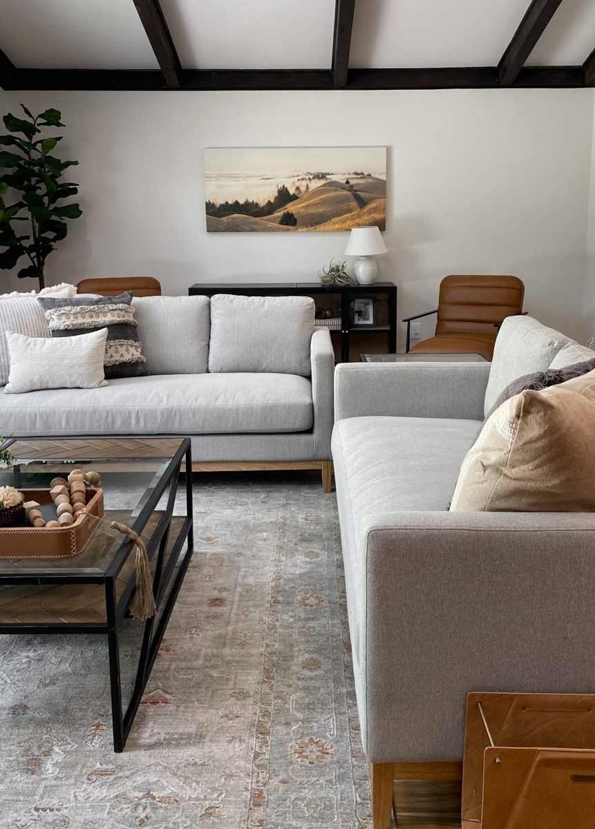 Fully staged living room space in a remodeled Pacific Palisades, California home with grey sofas, leather occasional chairs, ornate rug