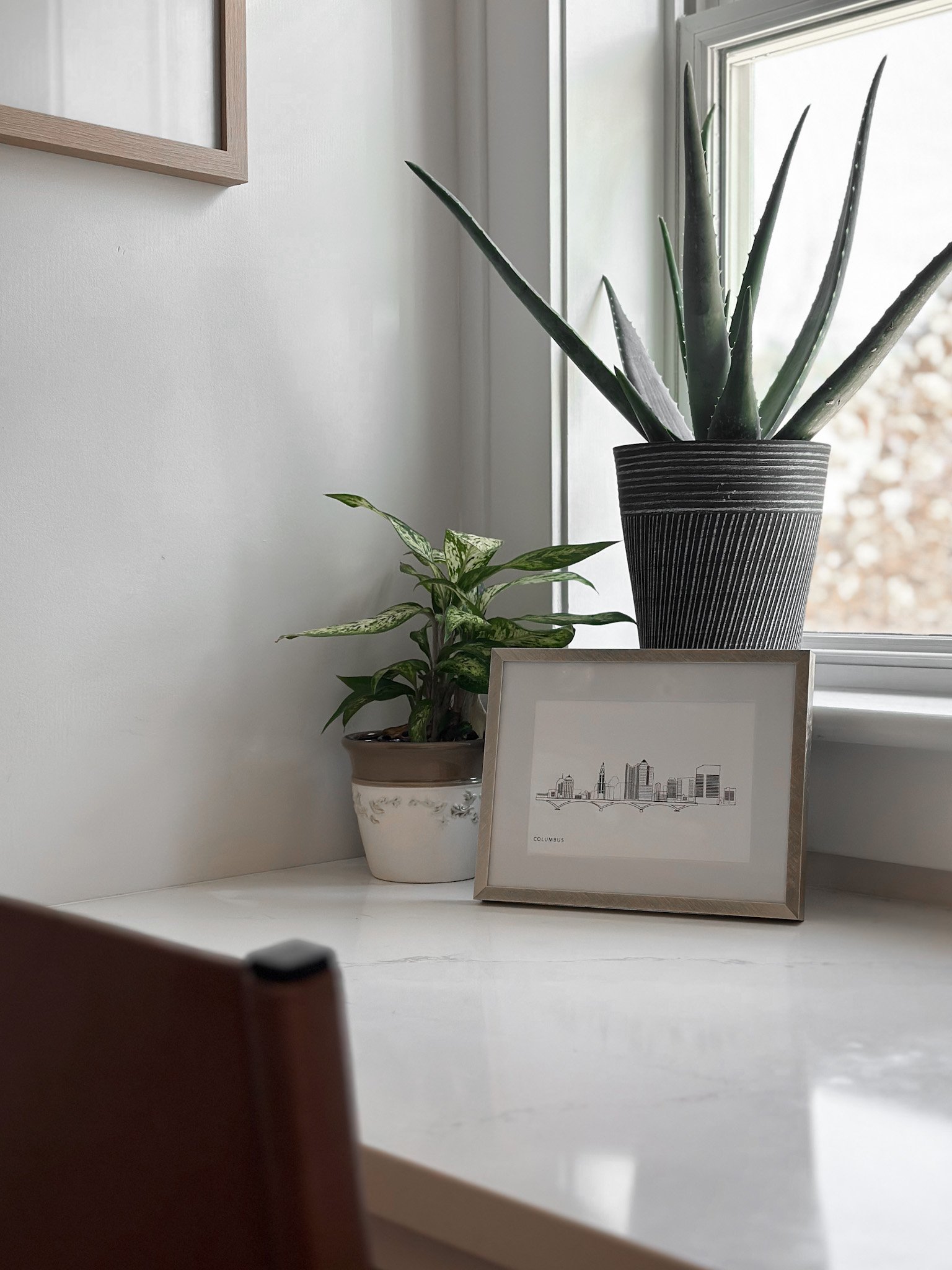 Nook of a Columbus home with a desk and potted plants with natural light from the window.