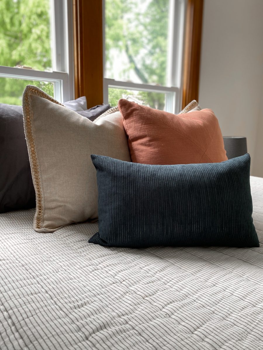 Bedroom pillow arrangement adds splashes of texture and color to a primary bedroom.