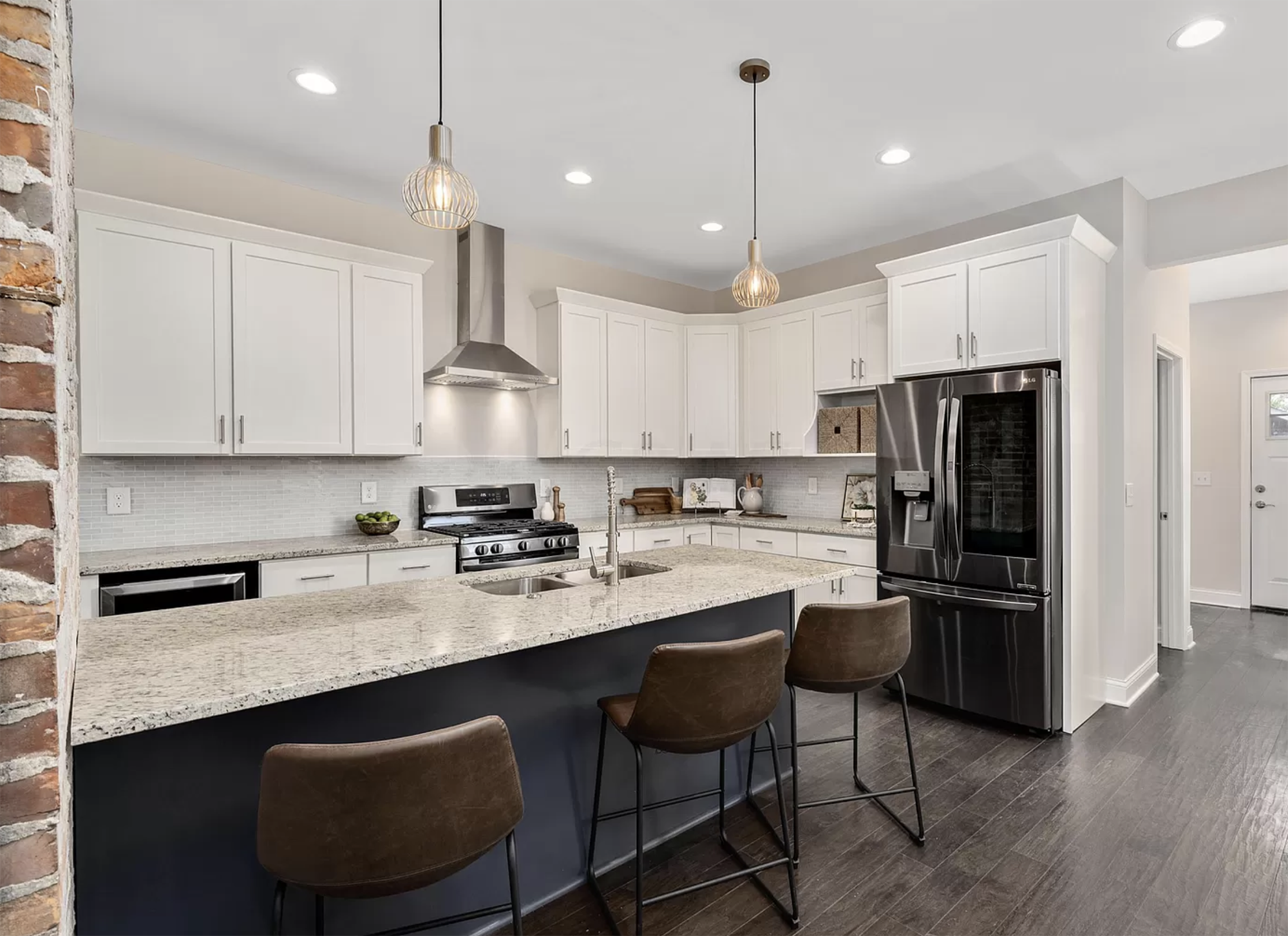 Remodeled kitchen with large LG refrigerator, granite countertops and leather backed bar-stools.
