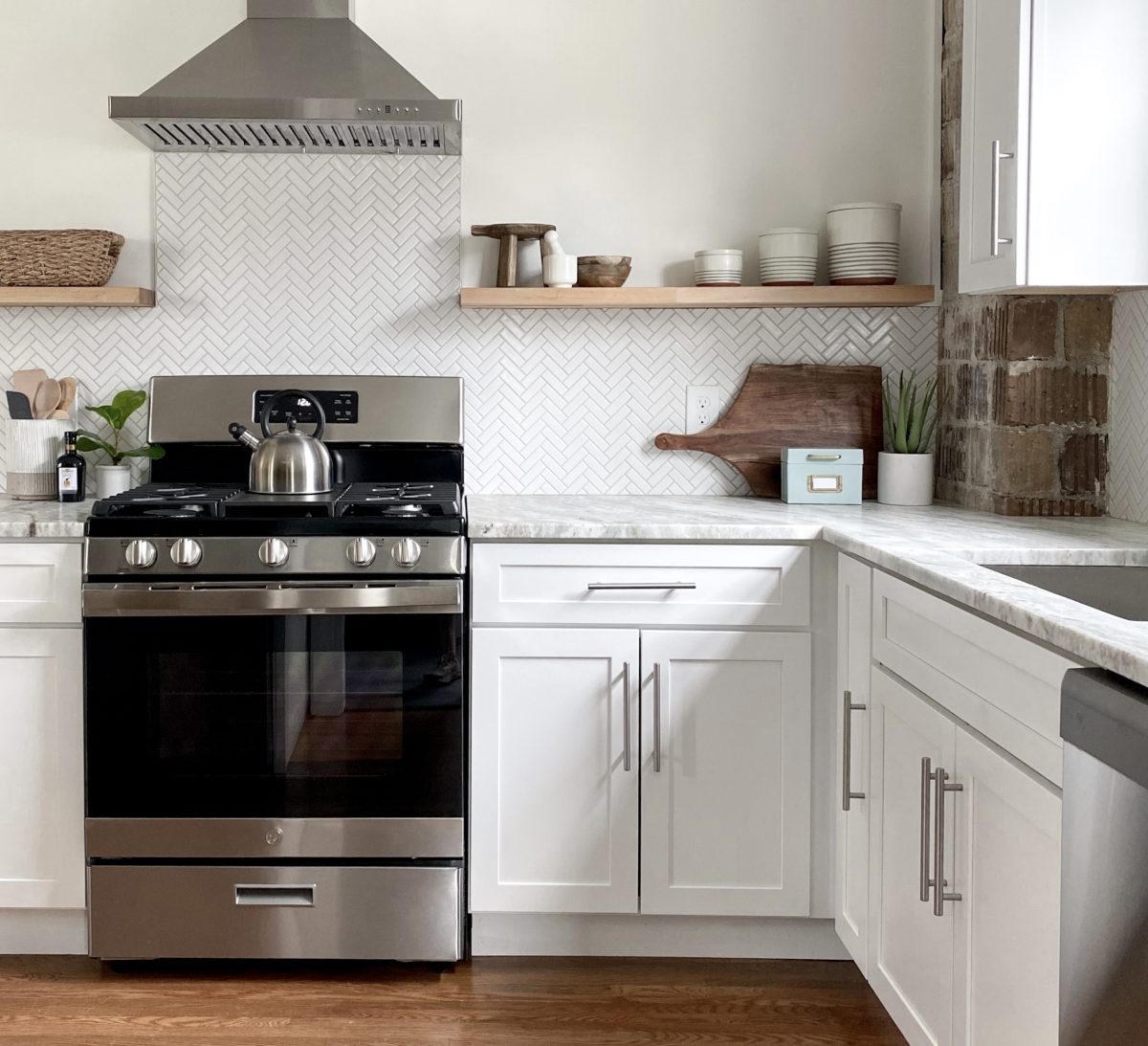 Fully remodeled kitchen with white granite countertops, stainless appliances, herringbone backsplash and natural decor.