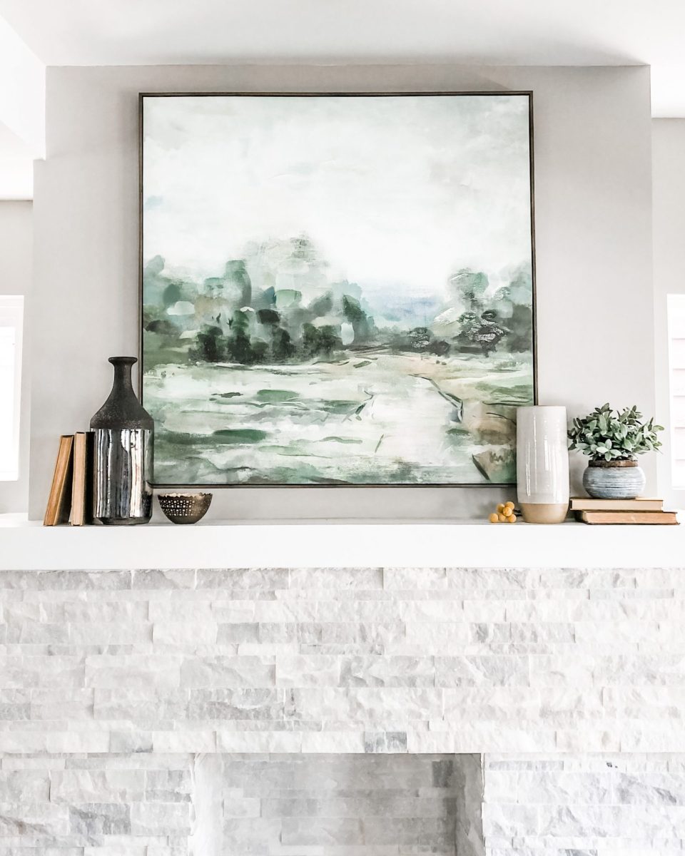 Large abstract artwork, vases and other unique decor turn a converted decorative fireplace in to a centerpiece in this home staging