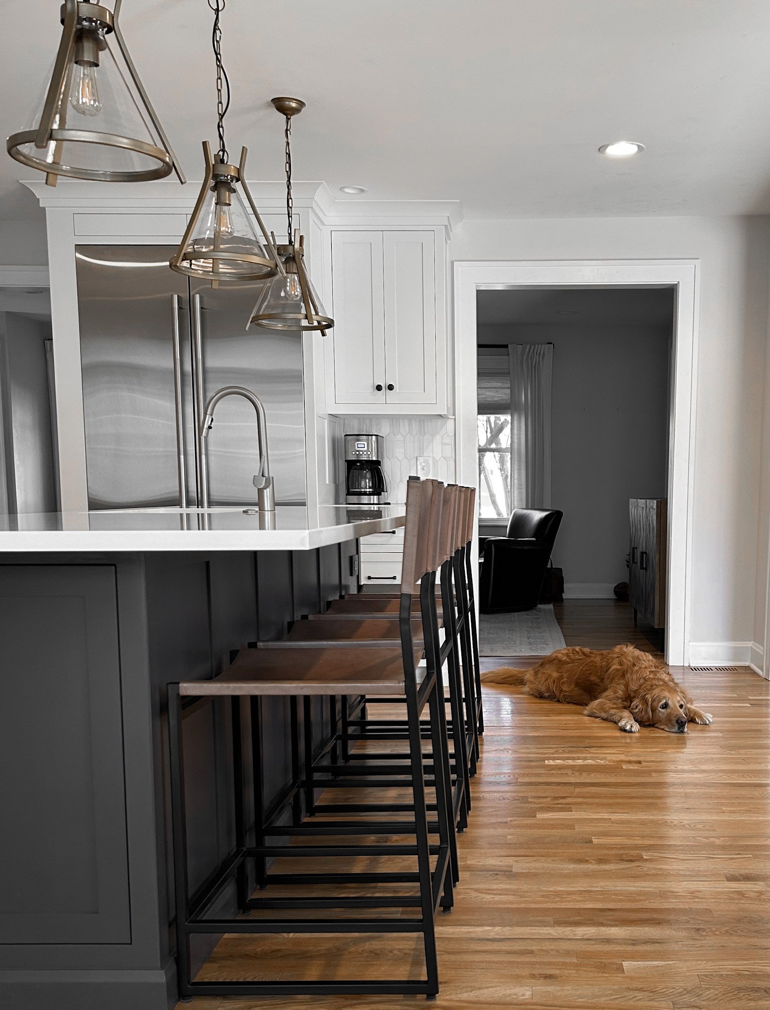 Modern kitchen interior design with leather high back barstools and a custom kitchen island with white countertops.