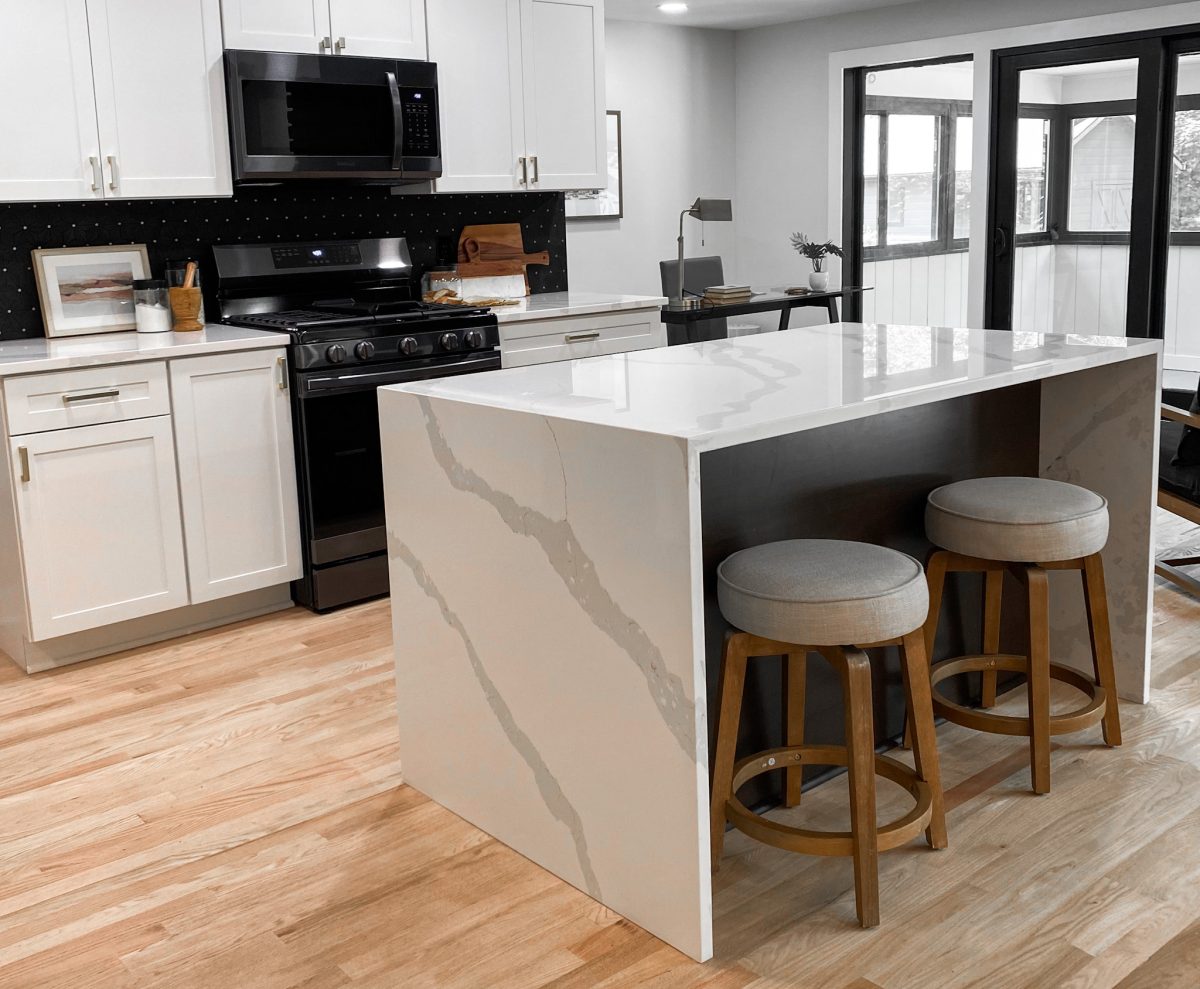 Barstools under a waterfall style solid surface kitchen island in a remodeled Pacific Palisades, California home.