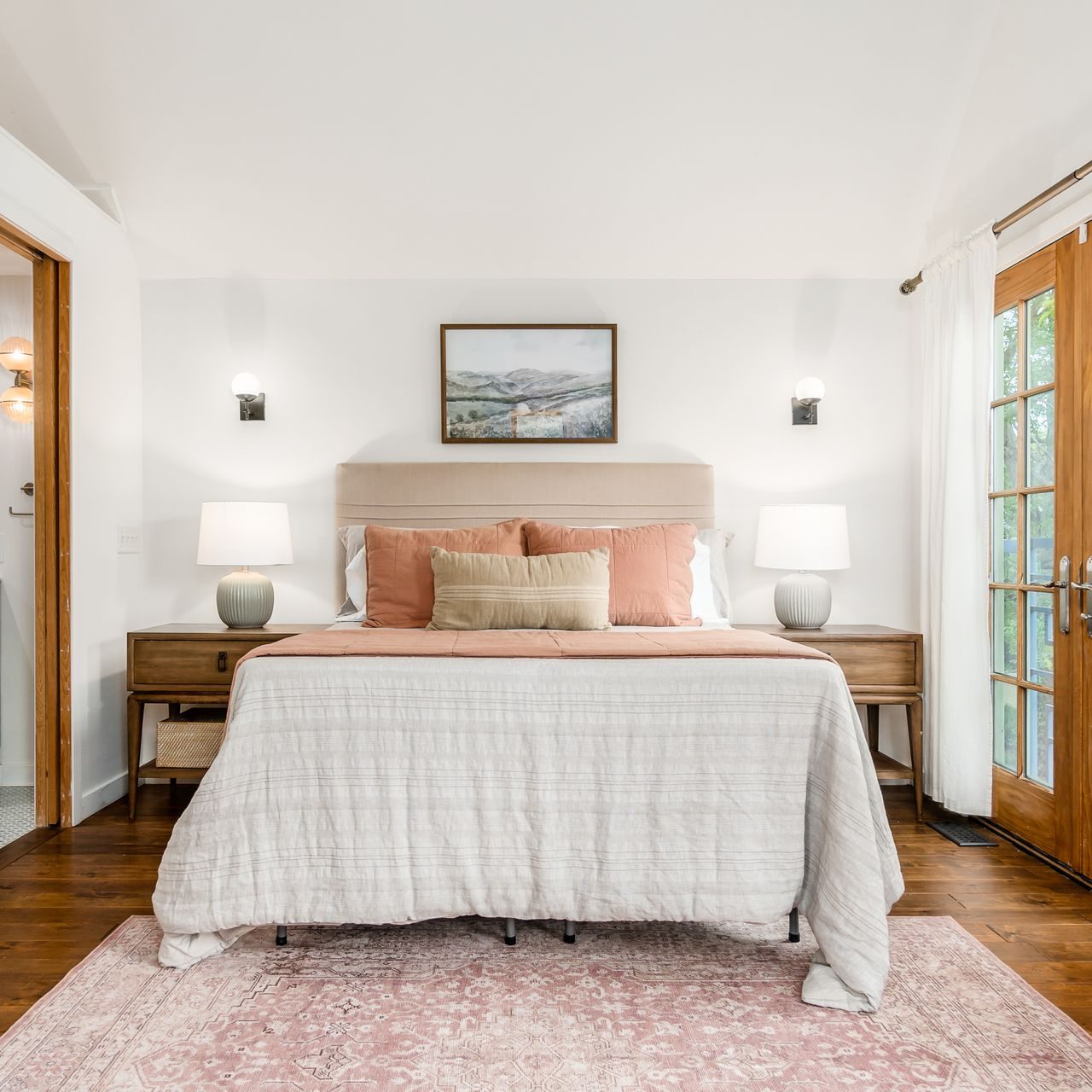 Stunning lofted bedroom in a historic German Village home in central Ohio staged with modern bedding, end table lamps and large area rug.