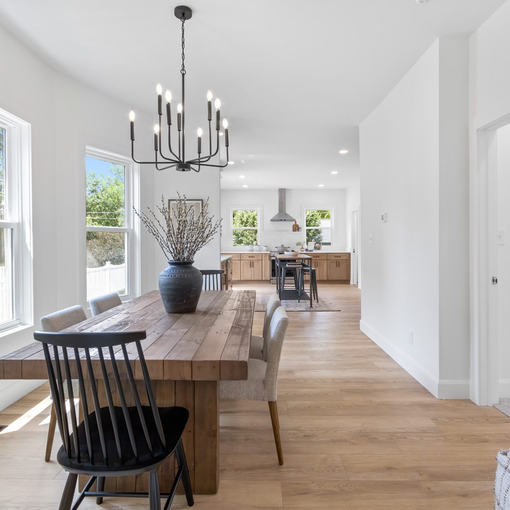 Modern dining space in a remodeled Pacific Palisades, California home featuring reclaimed wood table and large table vase.