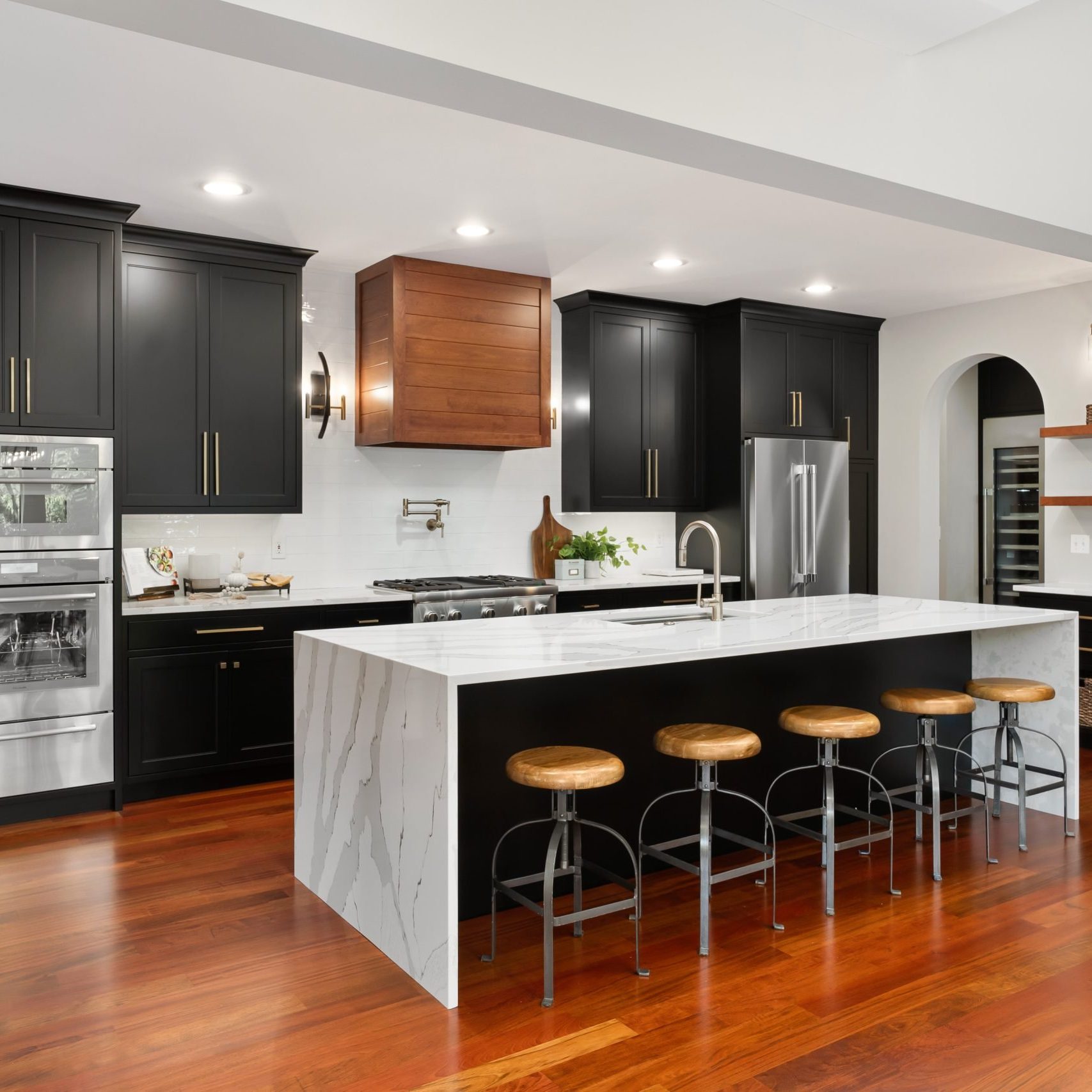Staging in the famous Muirfield Village golf course with large waterfall countertop, dark wood floors and custom black cabinetry.