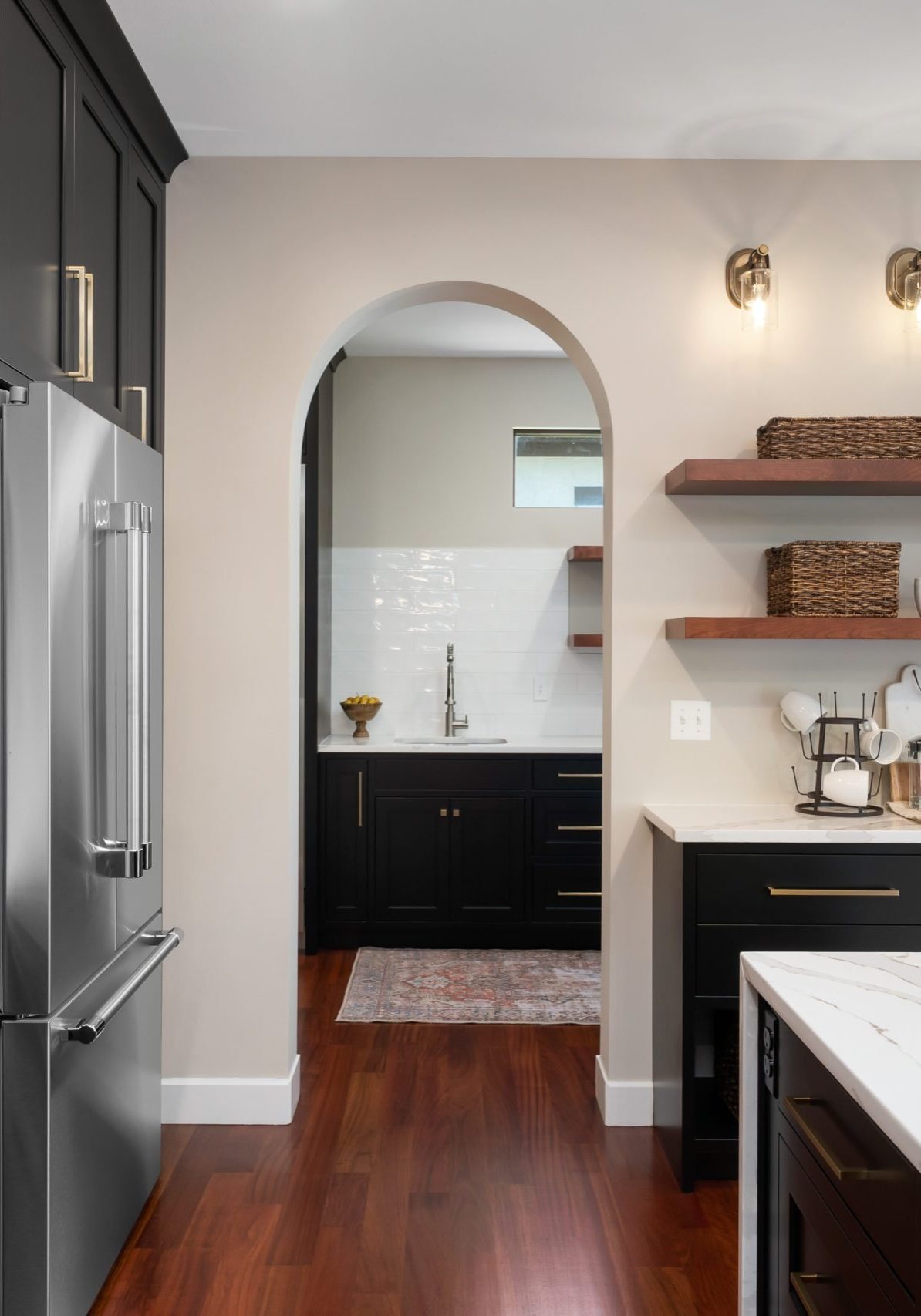 Kitchen into pantry with waterfall style kitchen island and walkway black custom cabinetry.