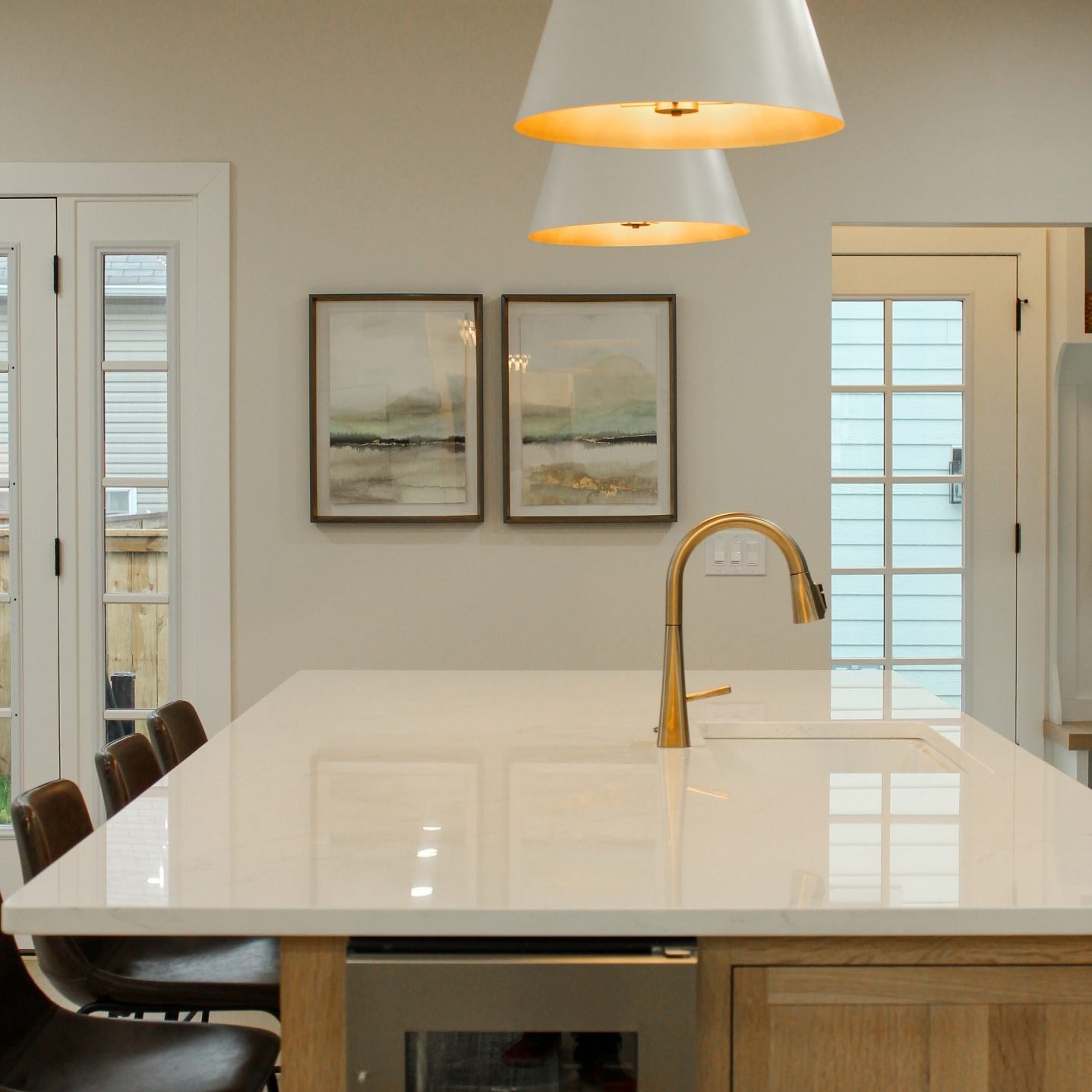 Remodeled kitchen in German Village Ohio with large pendulum lights, white island countertops, leather backed countertop stools and wine fridge.