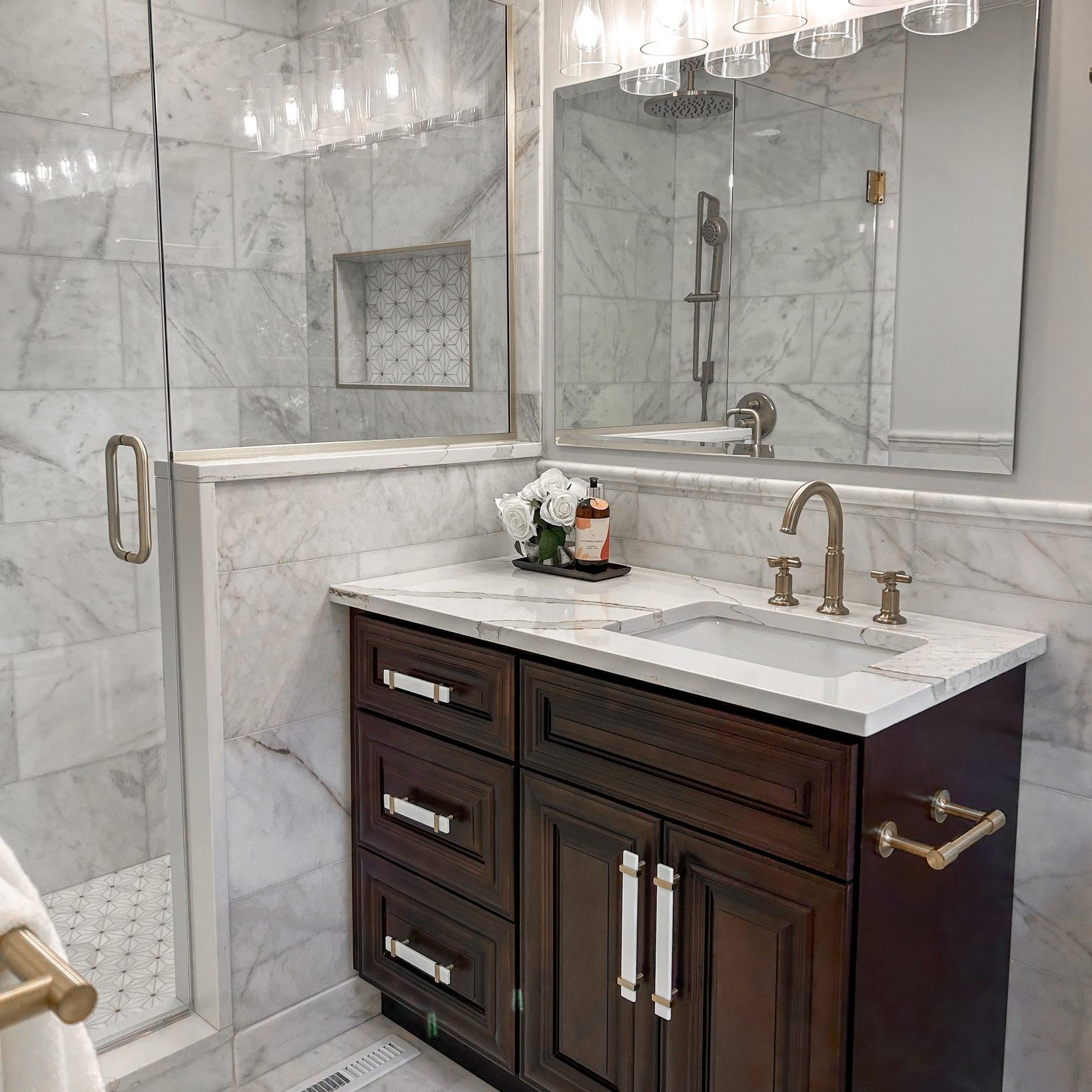 Redesigned luxury bathroom in Upper Arlington, Ohio, with marble tile, walk-in shower, and custom dark wood vanity.