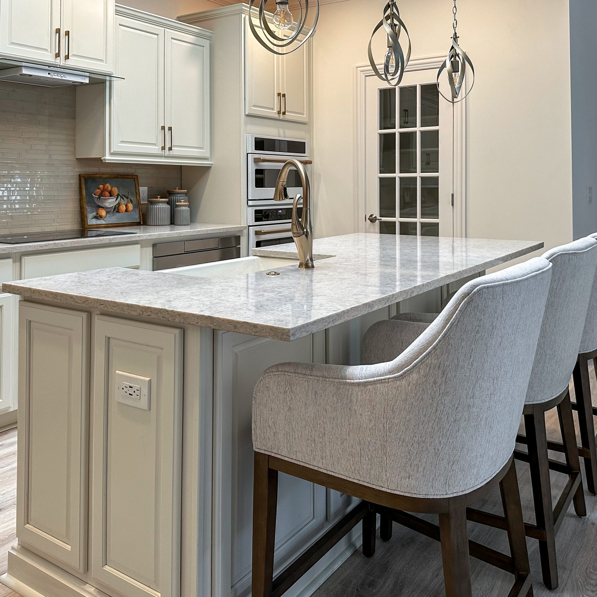 White themed kitchen island with high backed, upholstered bar stools and white granite countertops in luxury Dublin, Ohio, home.