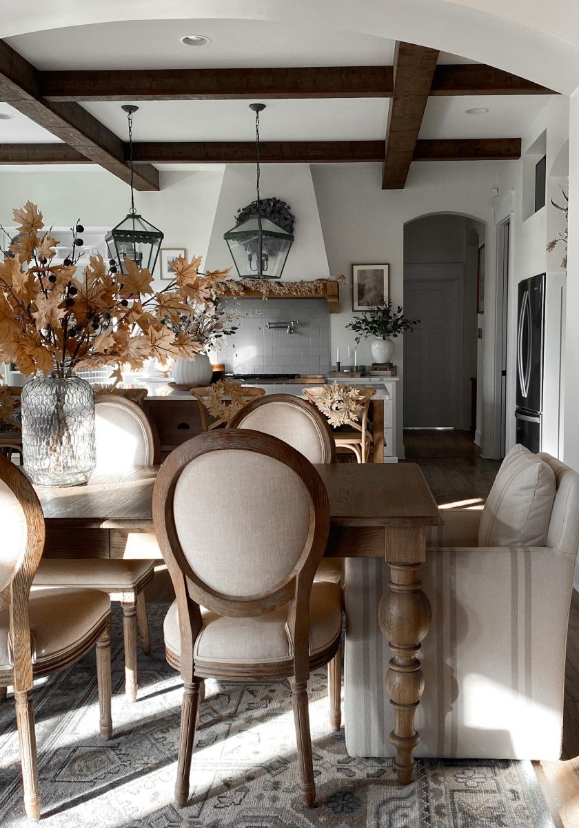 High coffered ceilings over a large natural dining room table and ornate area rug.