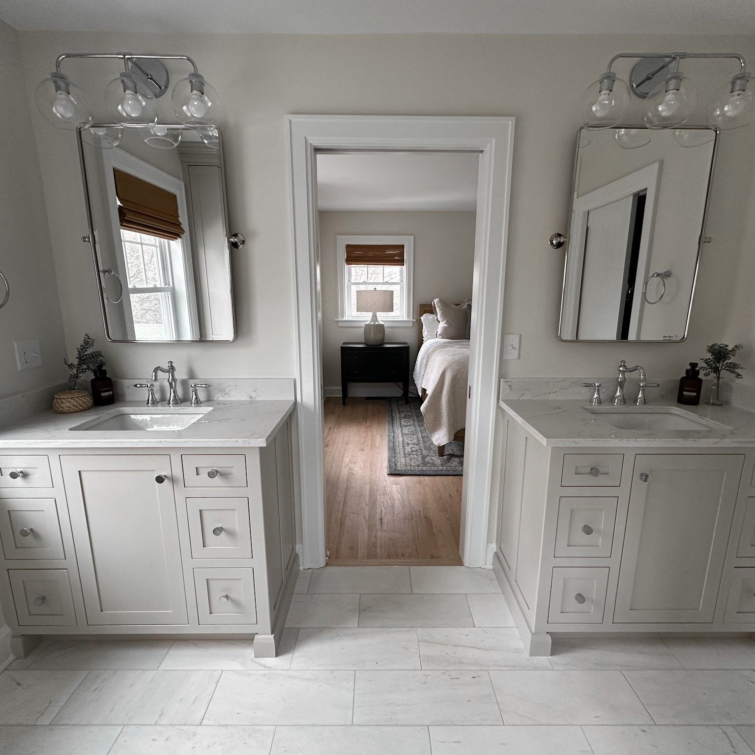 Large custom remodeled bathroom with double vanity, sconce lighting and white tile flooring.