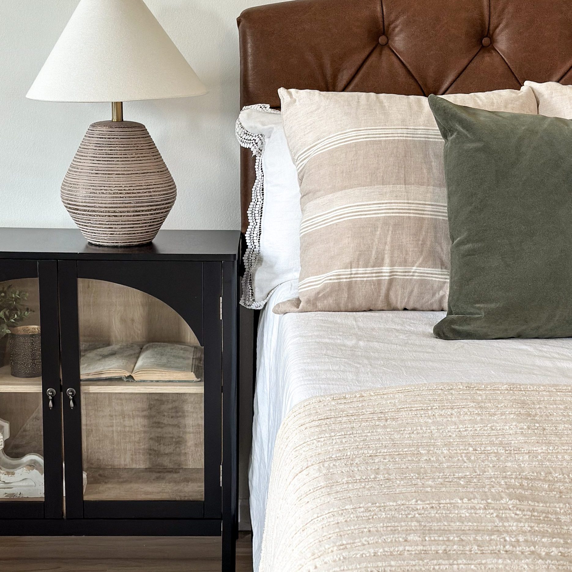 Dublin, Ohio, primary bedroom staging with leather tufted headboard, glass inlay nightstands and table lamps.