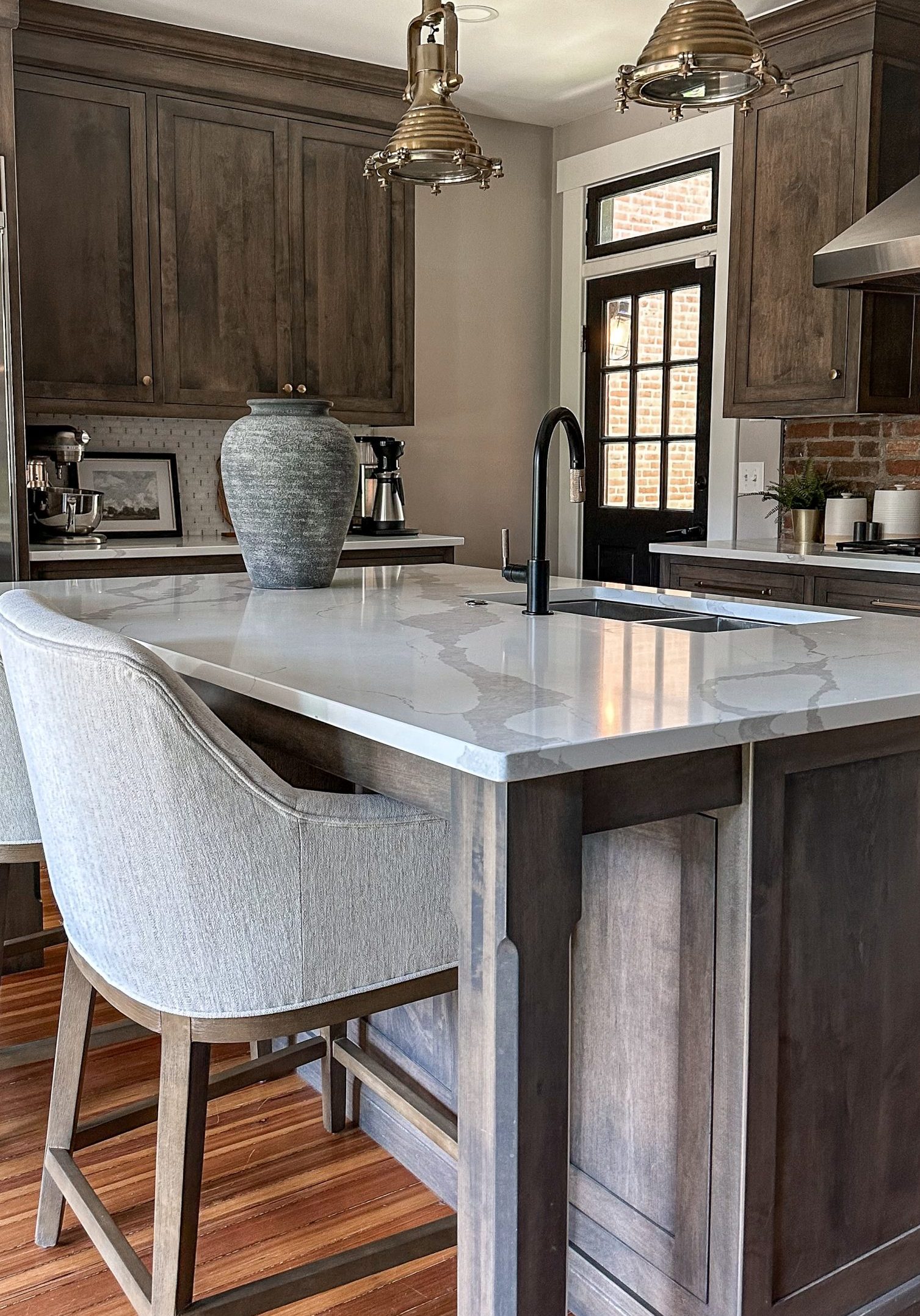 Remodeled kitchen with large granite island and upholstered counter-stools.
