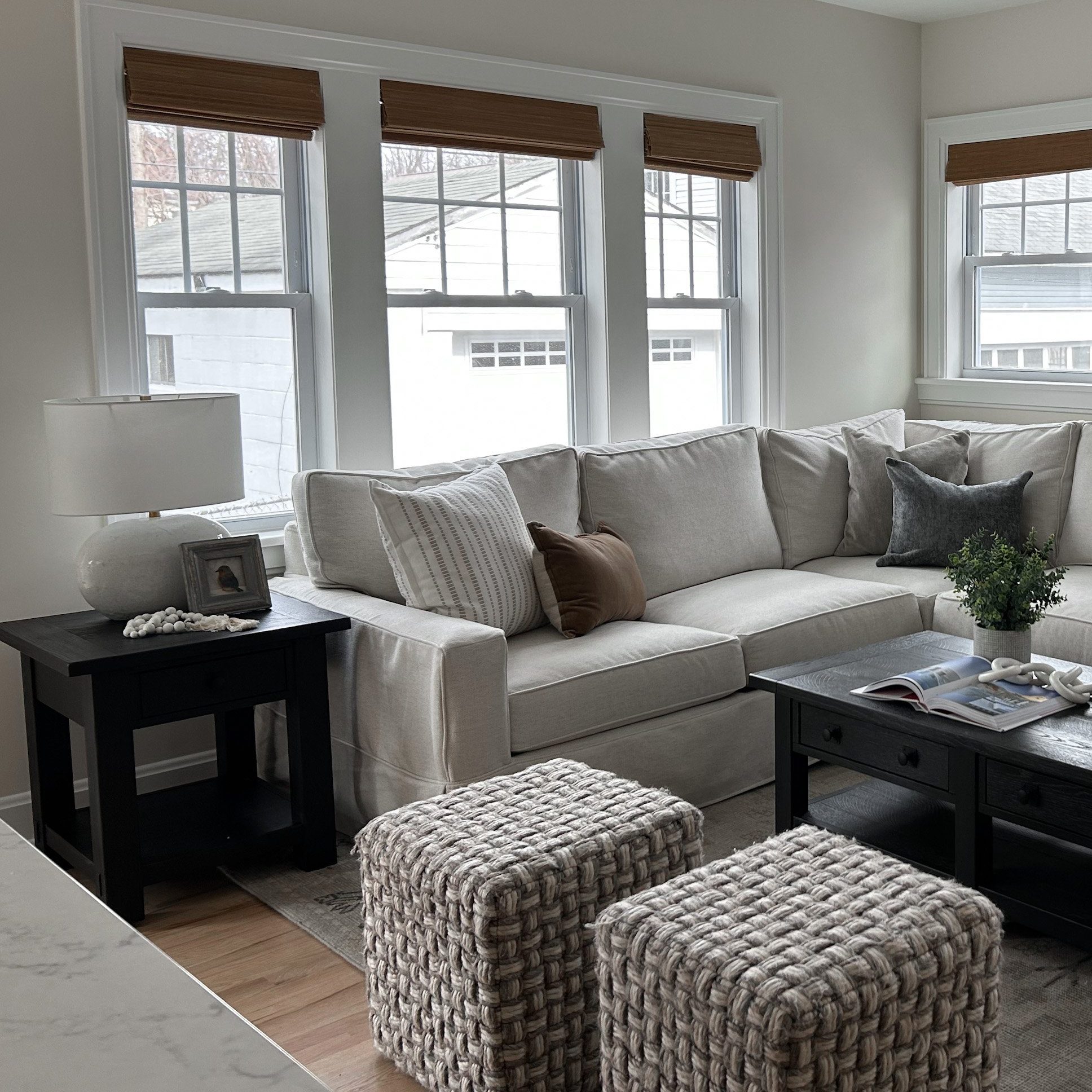 Light, comfortable living room design for residential interior design client featuring unique black stained coffee table and large sectional soffa.