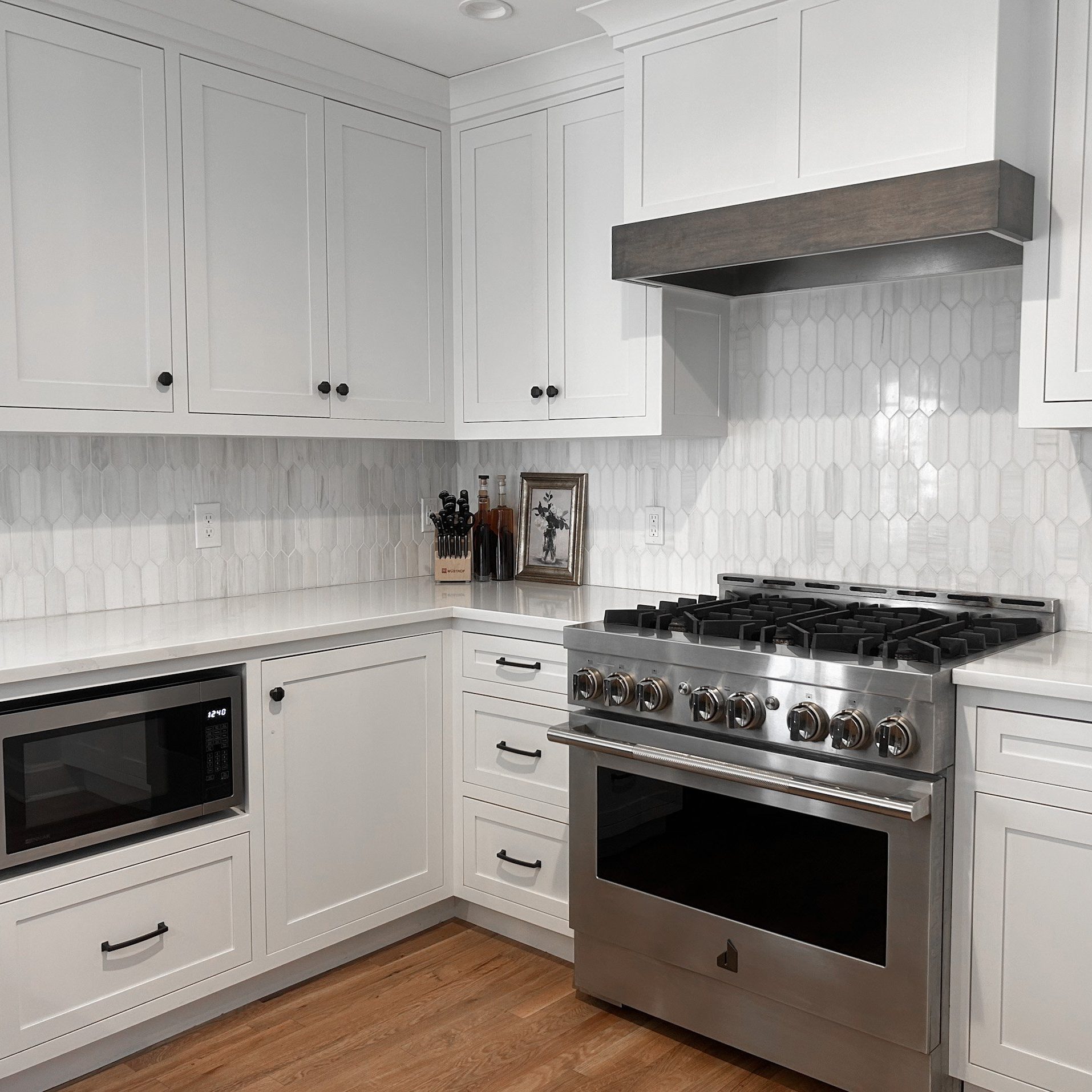 White themed kitchen area with white countertops. custom cabinets and white backsplash.