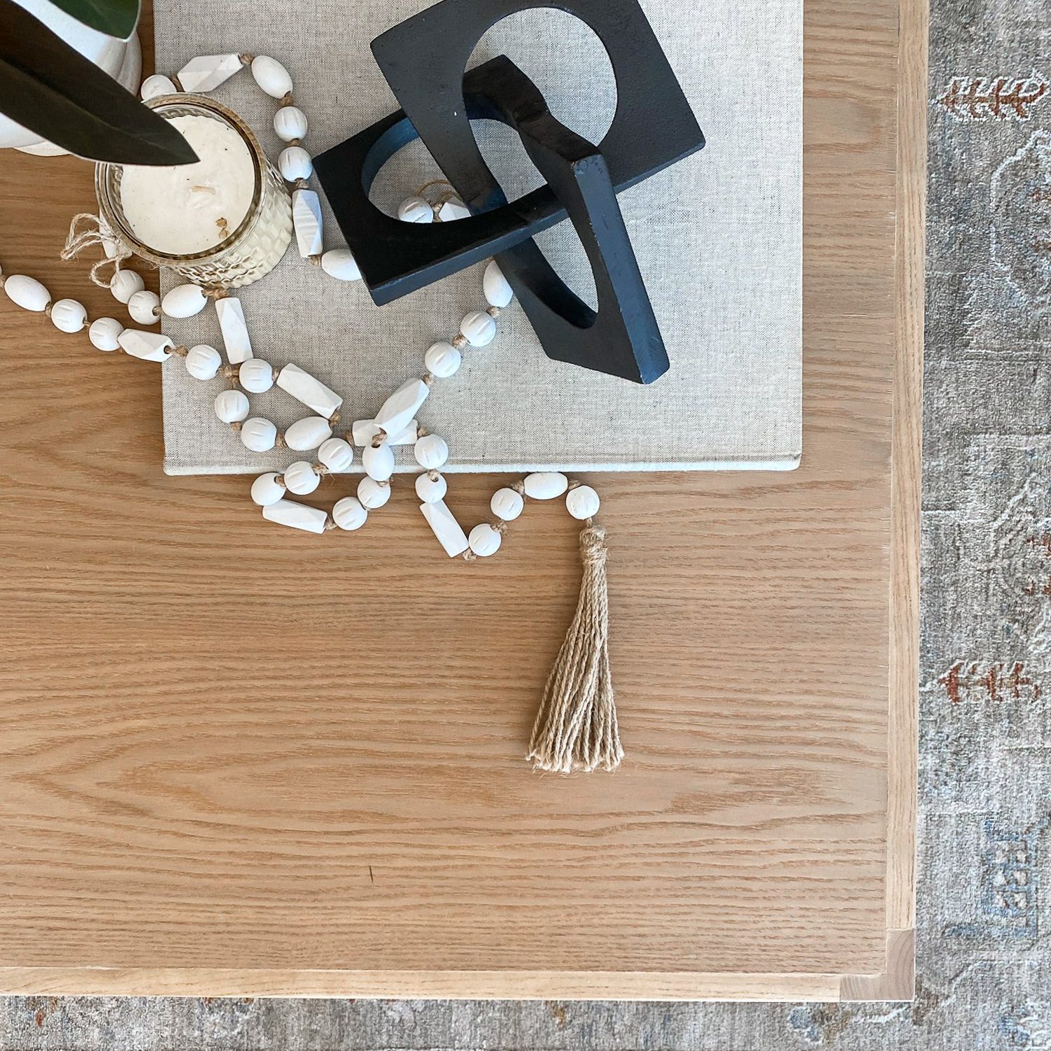 Table-scape on a wooden coffee table in a Pacific Palisades, California, staging with black table decor and white terra cotta beads.