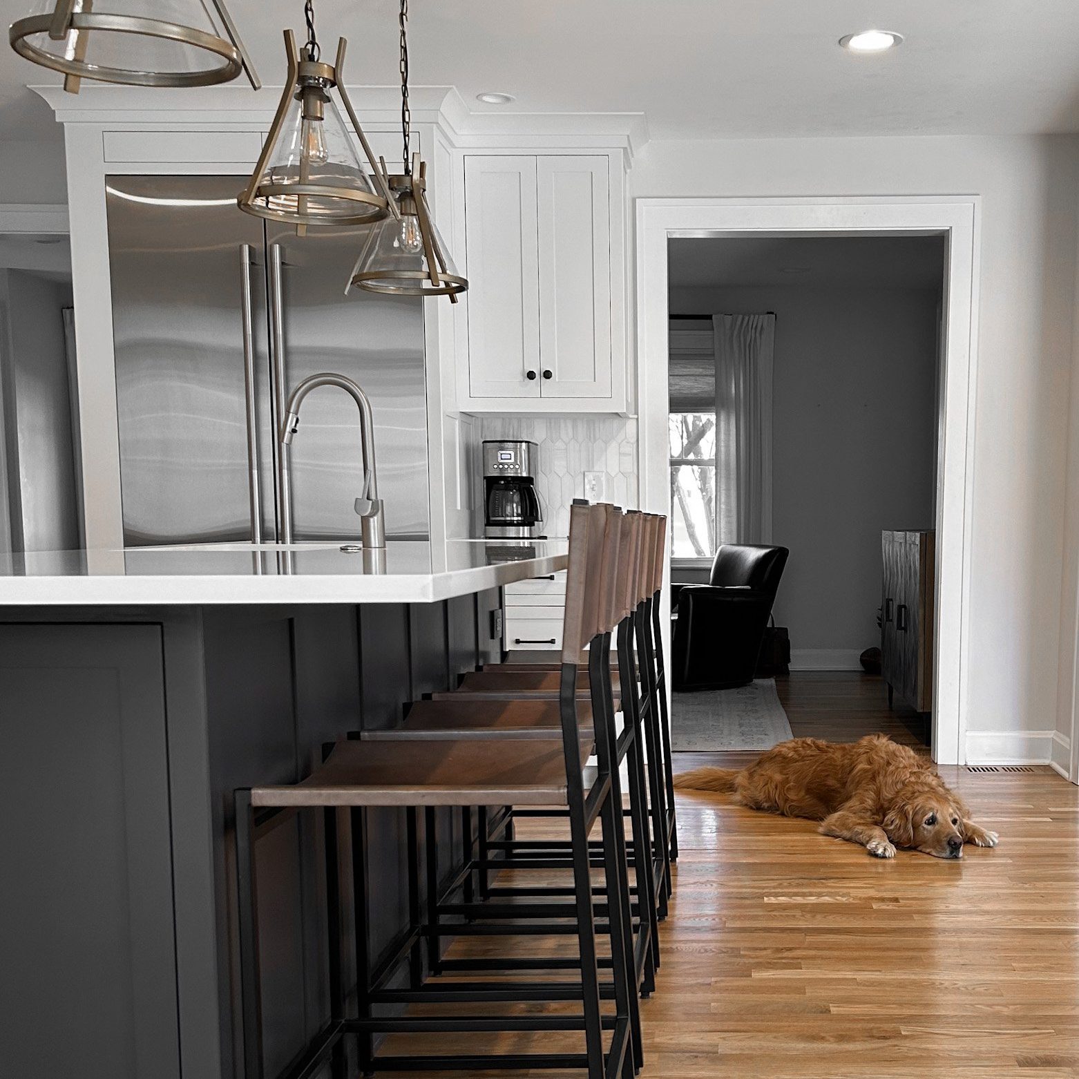 Modern kitchen interior design with leather high back barstools and a custom kitchen island with white countertops.